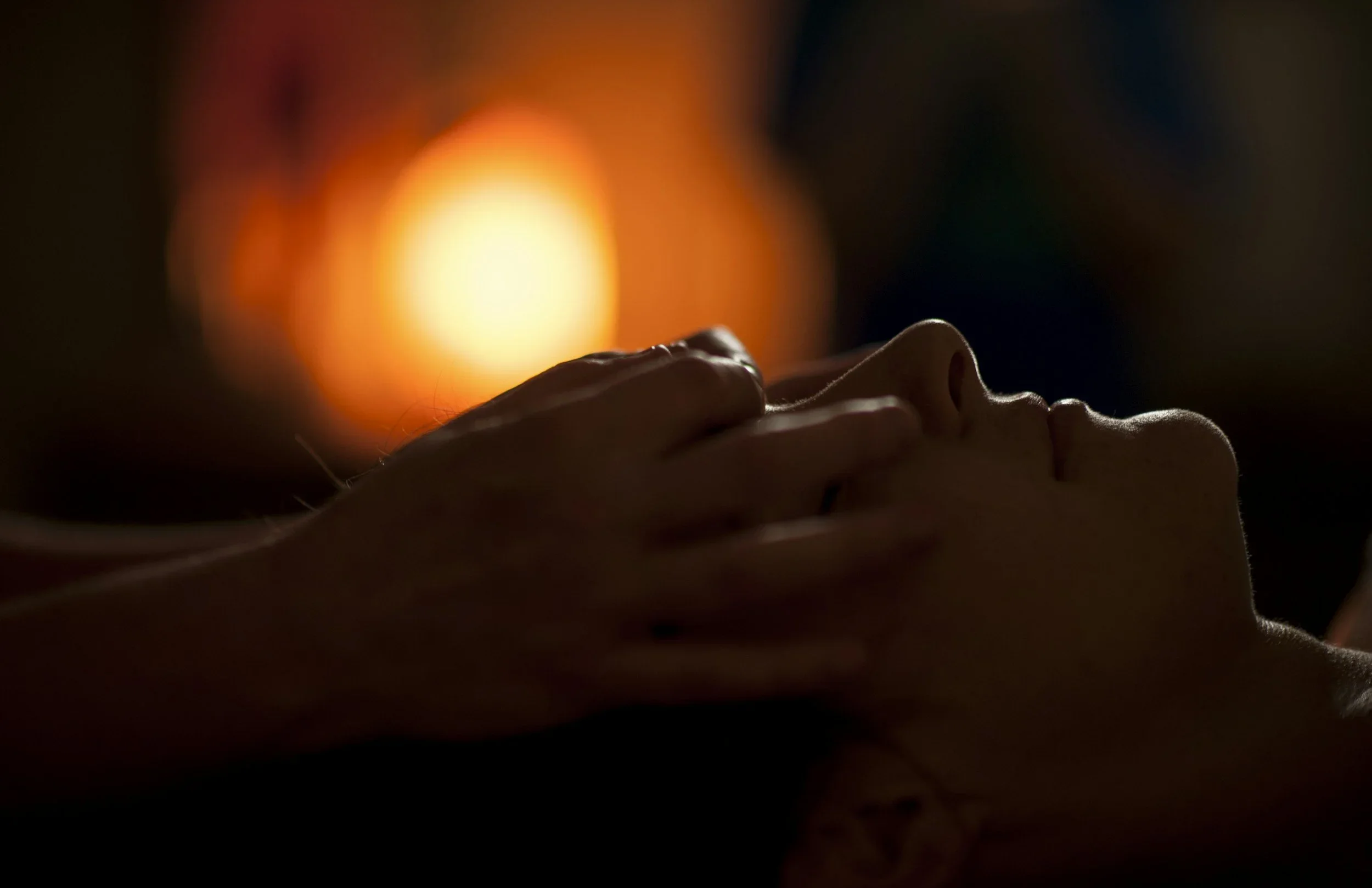A close-up view of a persons face while receiving a soothing reiki treatment in-person.