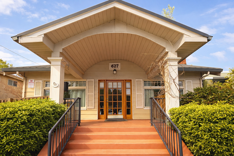 Front view of a house with a wooden front door, staircase, and a large arched porch roof. This is where 144 Miracles Reiki is located