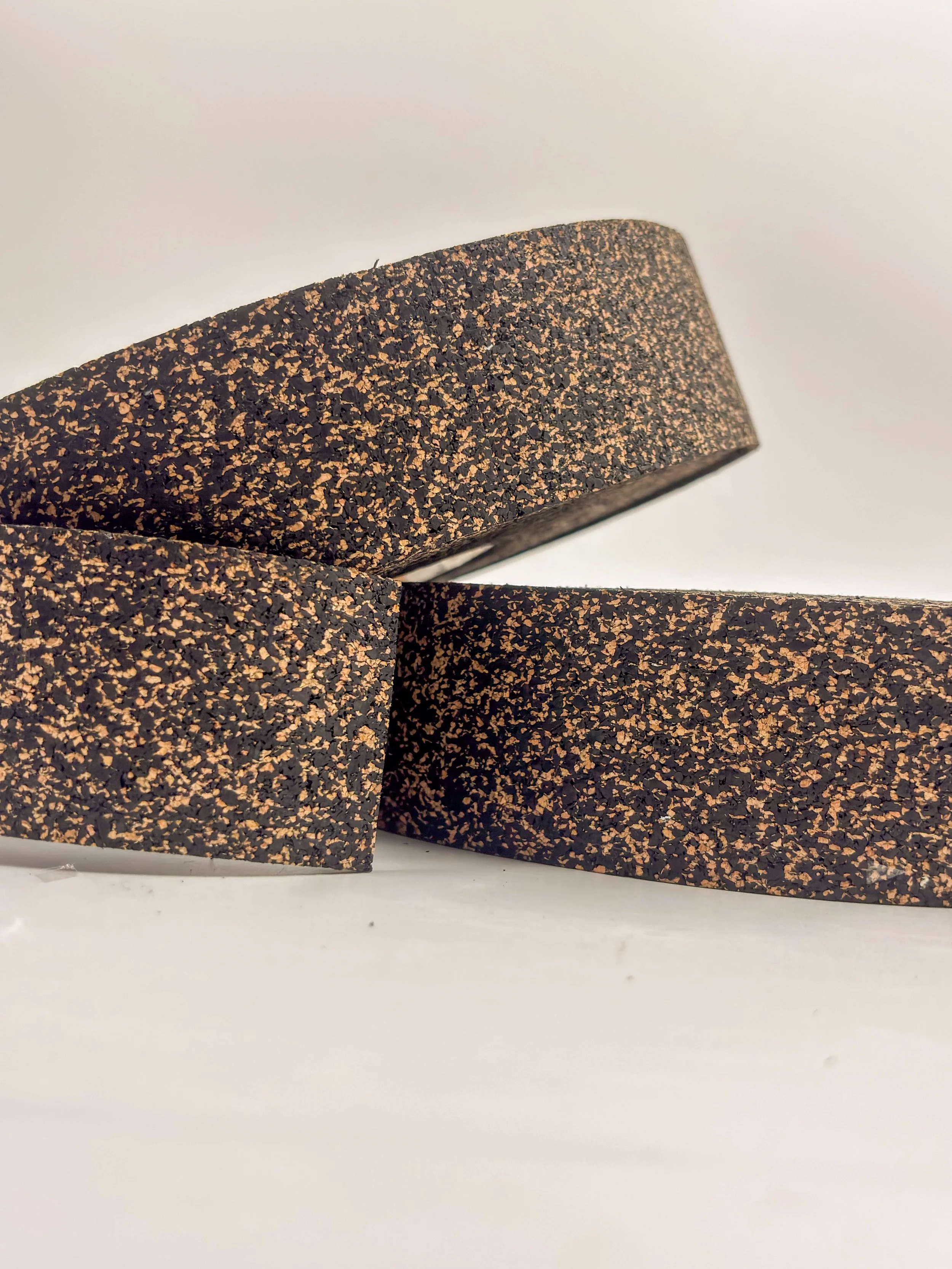 Three black and brown speckled rubber cork yoga blocks on a white surface.