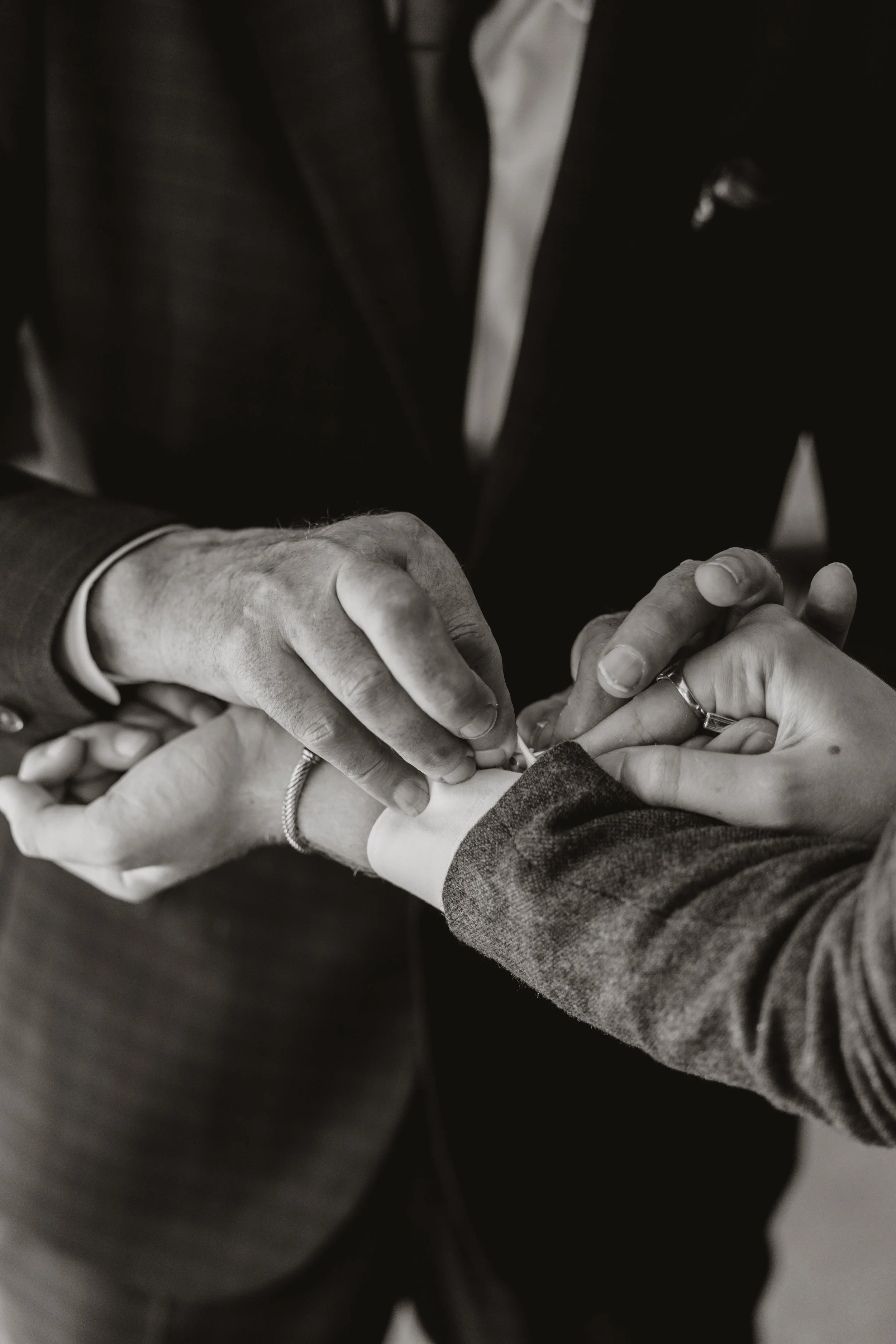 Two people exchanging a ring during a wedding ceremony, one person is helping the other put the ring on their finger.