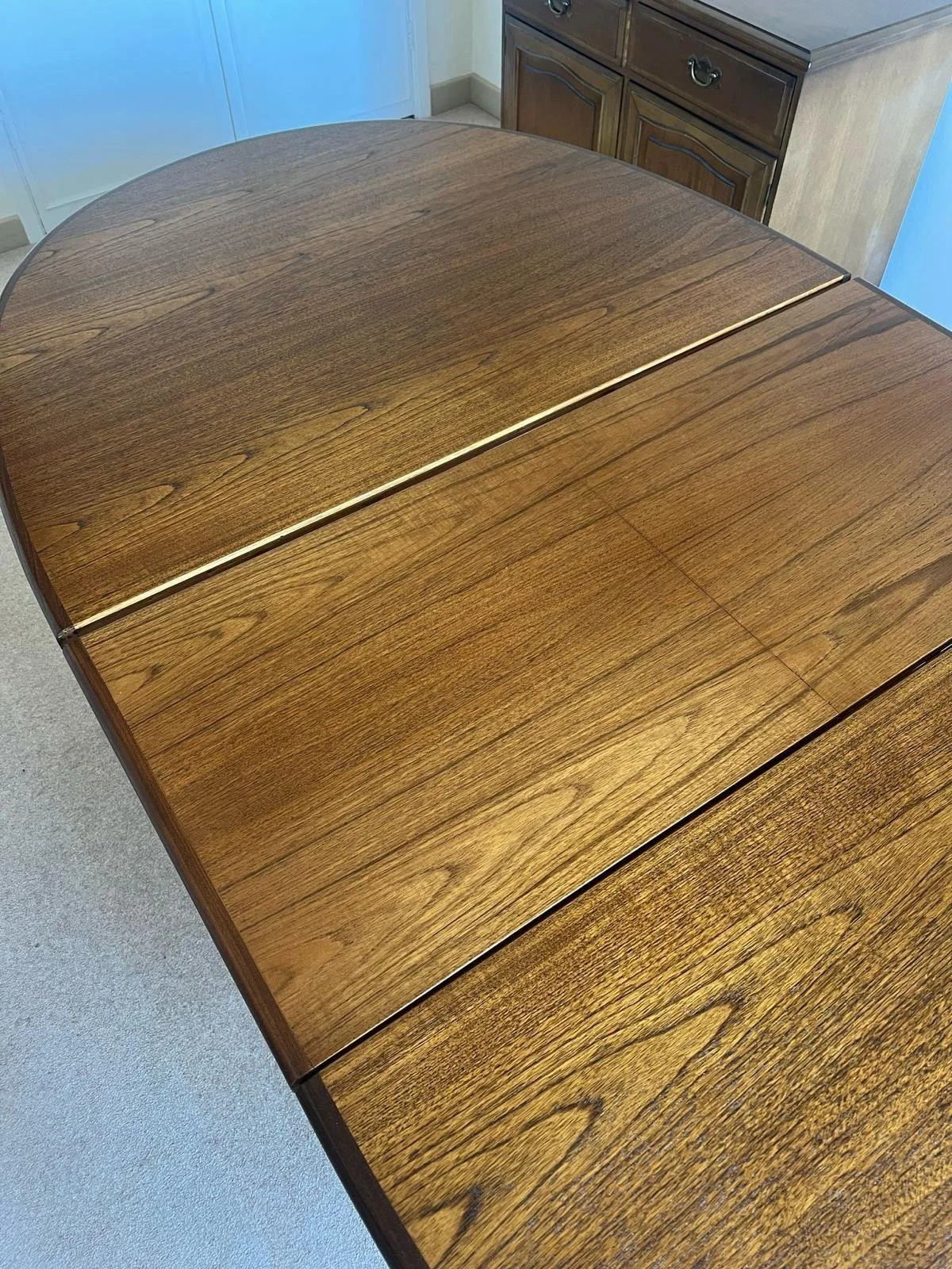 Wooden dining table with a fold-out leaf extension in a kitchen area.