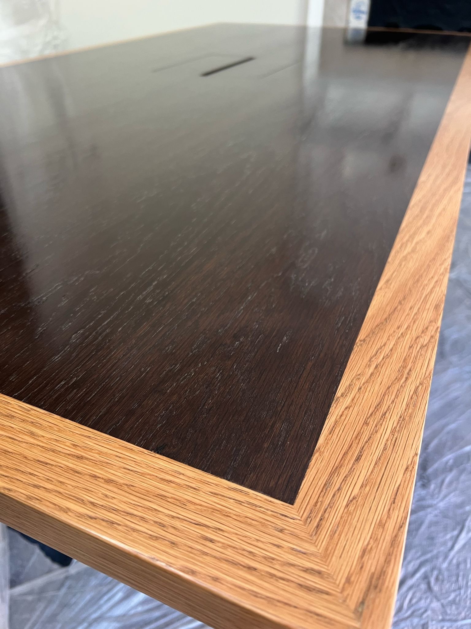 Close-up of a wooden table with a dark wood top and a lighter wood border.
