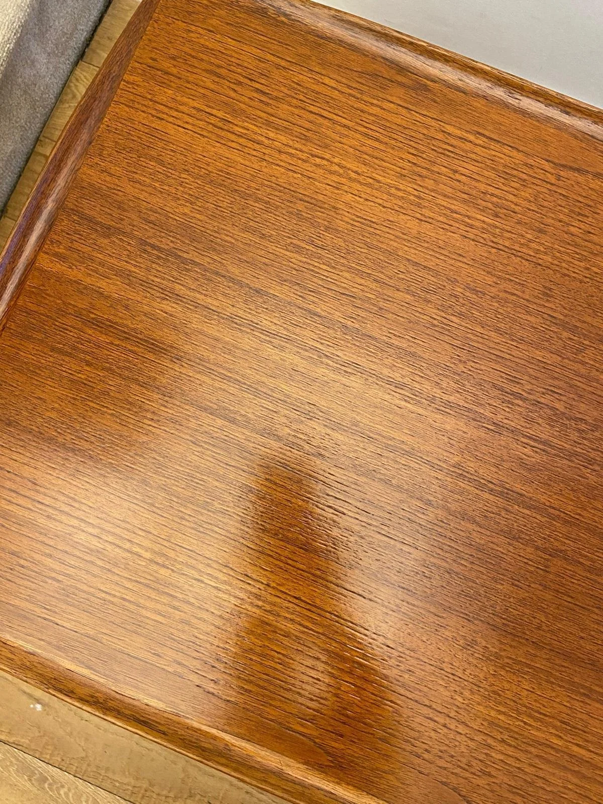 Close-up of a polished wooden table with visible wood grain and a rounded edge.