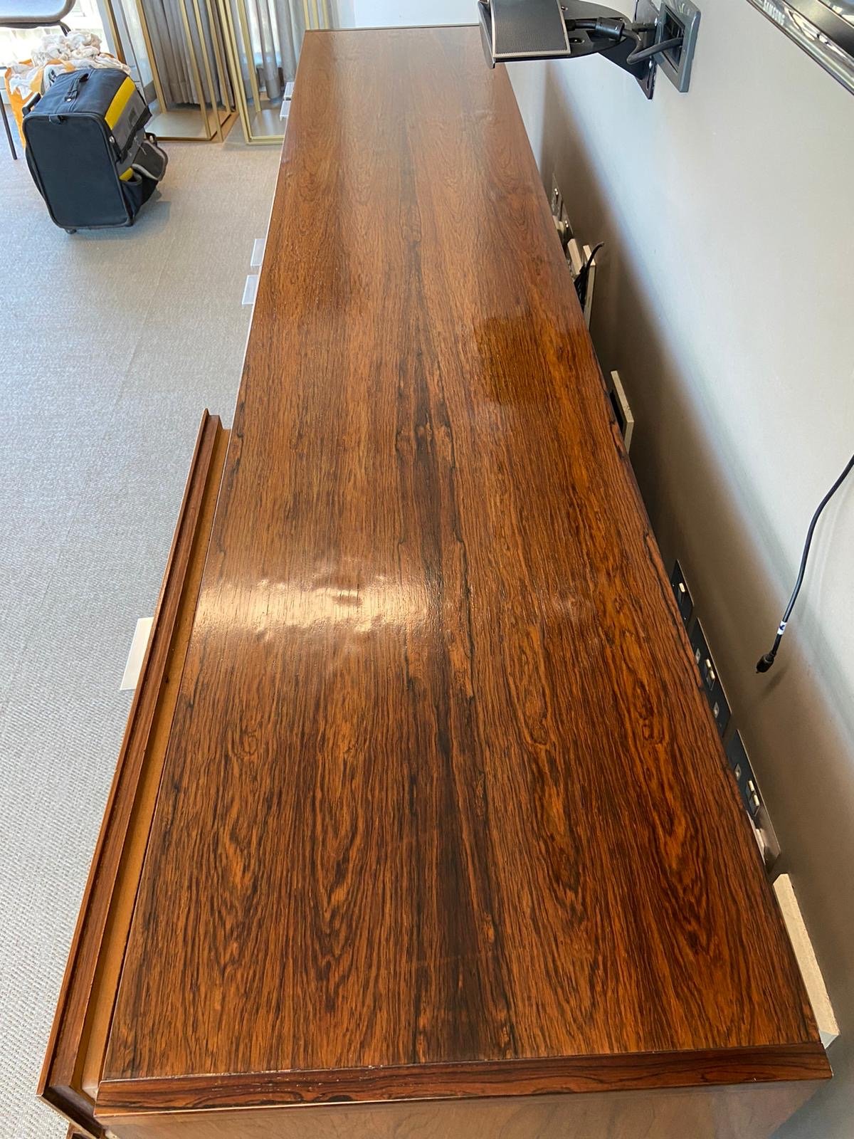 A long wooden conference table in a modern office with power outlets on the side.