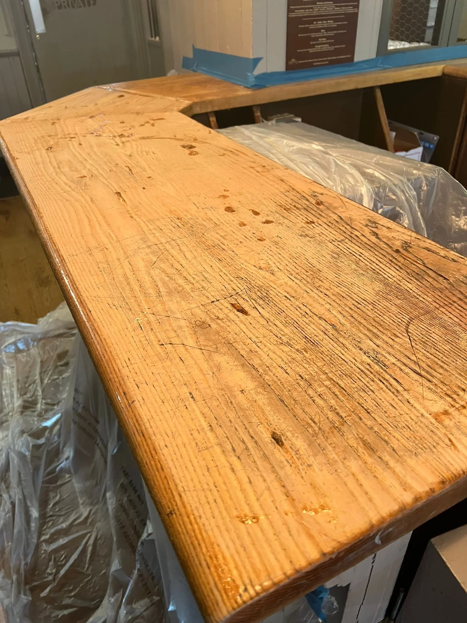 Close-up of a stained wooden countertop under construction with plastic protective sheeting underneath.