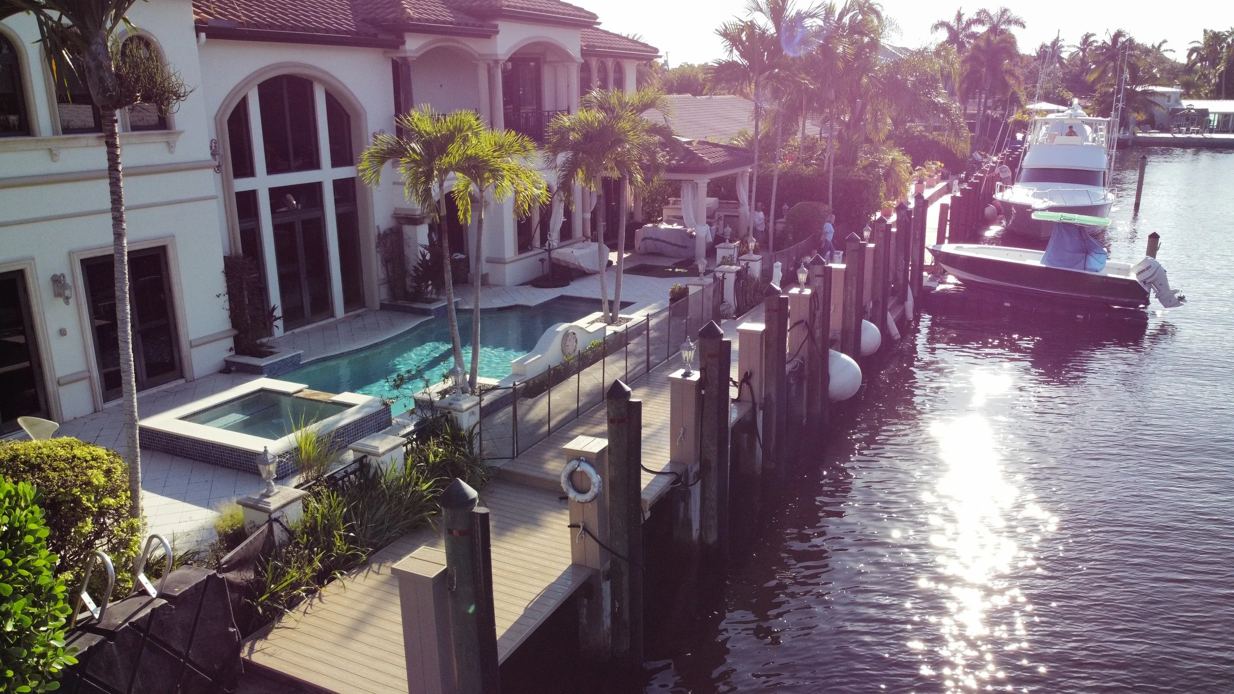 High-angle aerial view of a custom luxury South Florida waterfront estate featuring a complex, engineered decking and pier system, designed and built by JKT Marine or sophisticated coastal living. The installation Includes premium decking and pilings