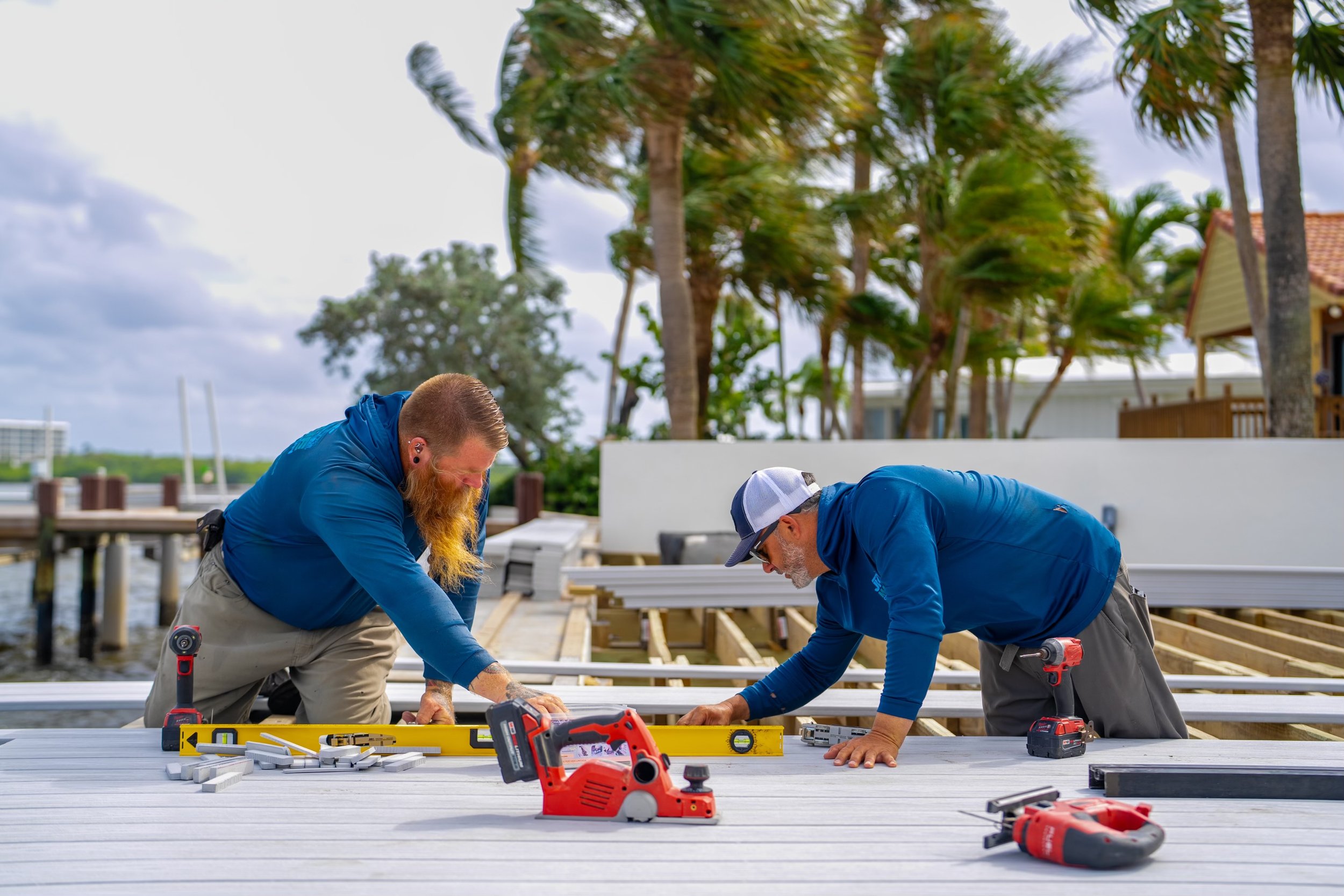 Custom deck construction, marine contractors South Florida, expert craftsmanship. Professional marine contractors from JKT Marine performing precision leveling and installation on a custom high-end waterfront deck in South Florida.