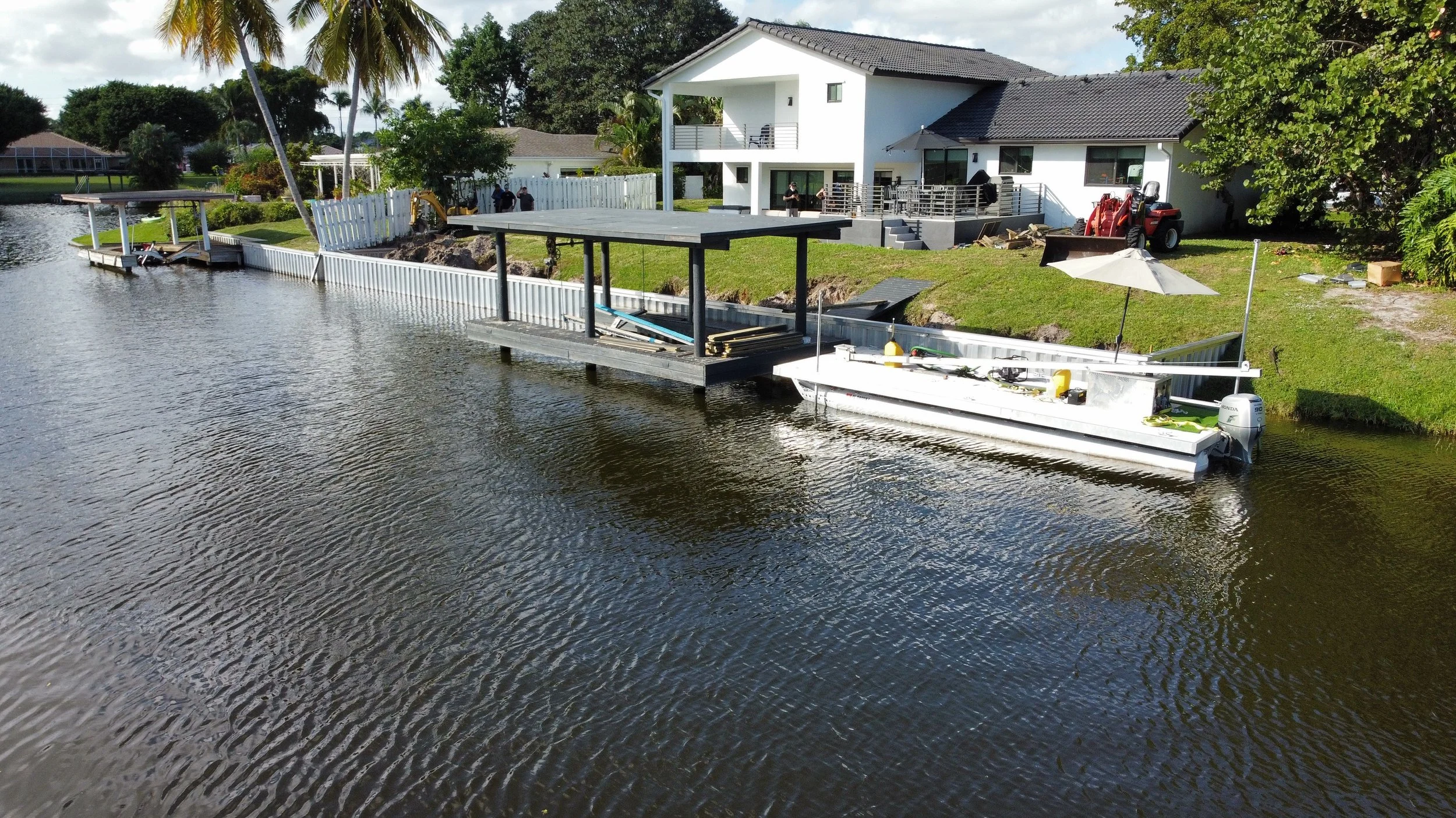 Comprehensive shoreline fortification project by JKT Marine in South Florida, featuring a precision-engineered vinyl seawall installation, integrated boat lift structure, and professional site excavation for long-term erosion mitigation.