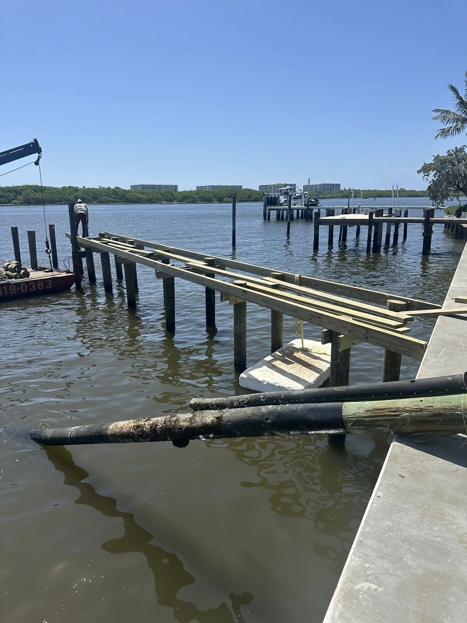 Expert maritime structural assembly by JKT Marine, showcasing the precision installation of high-capacity wooden dock joists and support pilings for a custom waterfront project.