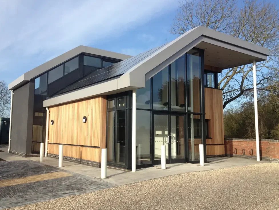 A modern building with wooden architiecture and huge glass doors and windows covering the front of the building