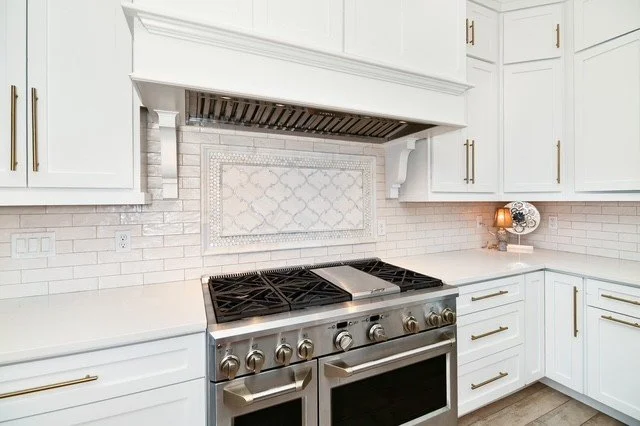 Modern kitchen with white cabinets, a stainless steel stove, and a decorative tile backsplash.