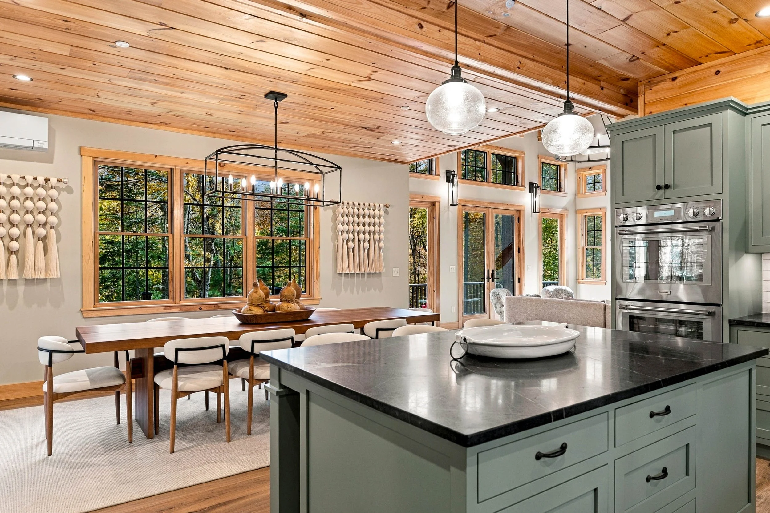 Thoughtfully designed for gathering, the kitchen, dining, and living spaces flow seamlessly beneath beautiful wood ceilings.