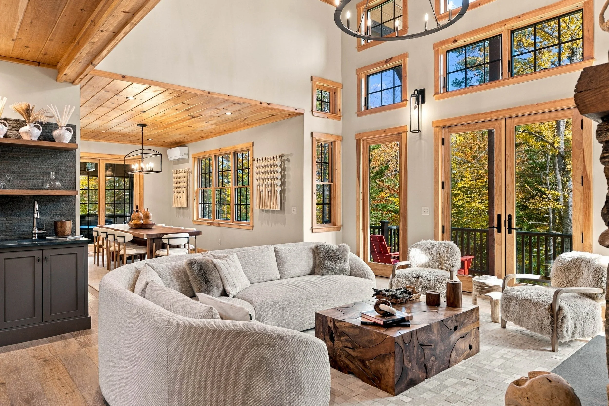 Gather beneath soaring ceilings beside the stunning stone fireplace, surrounded by expansive windows and natural light.