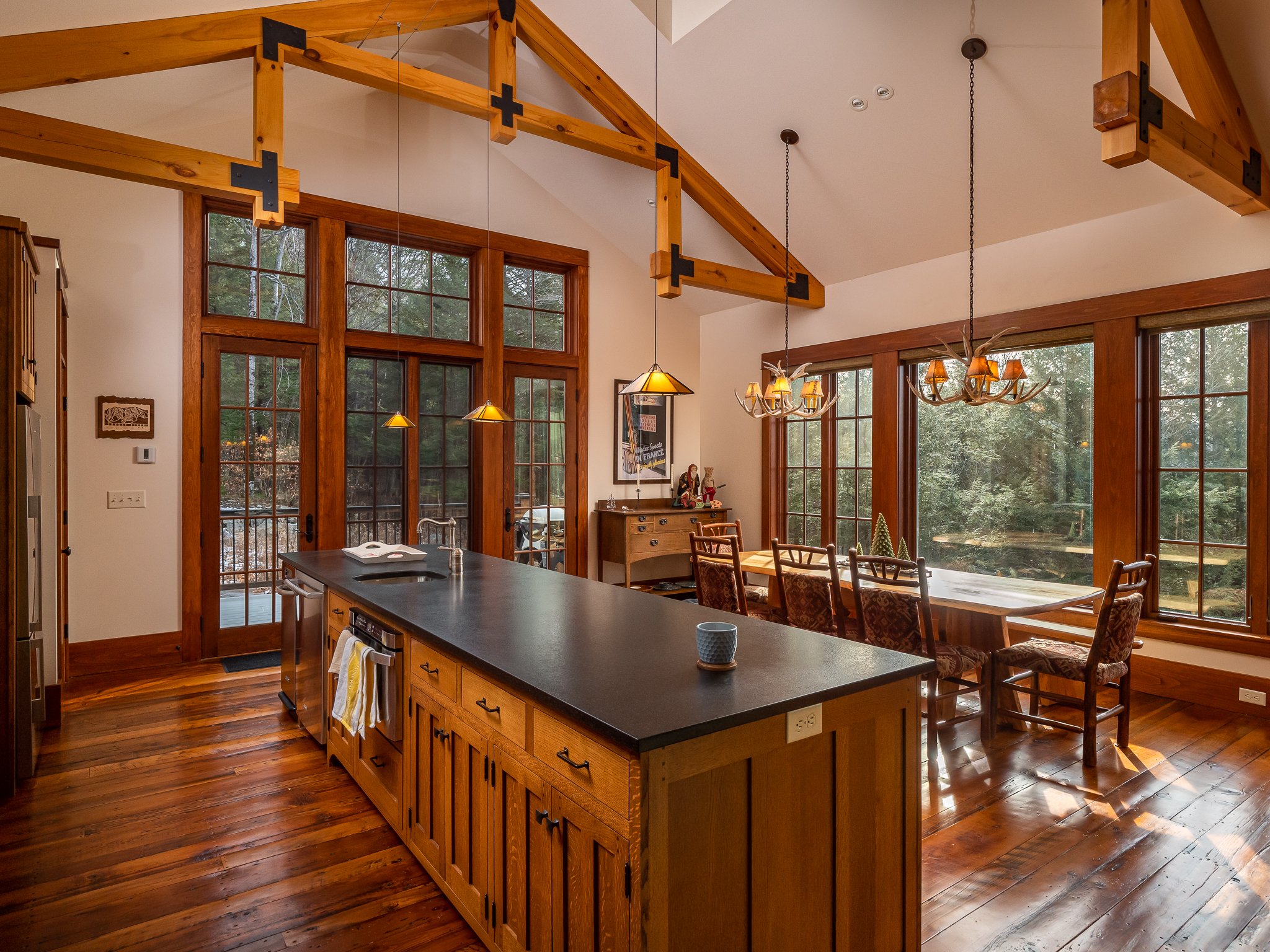 Rustic kitchen with wooden beams, large windows, and an island.
