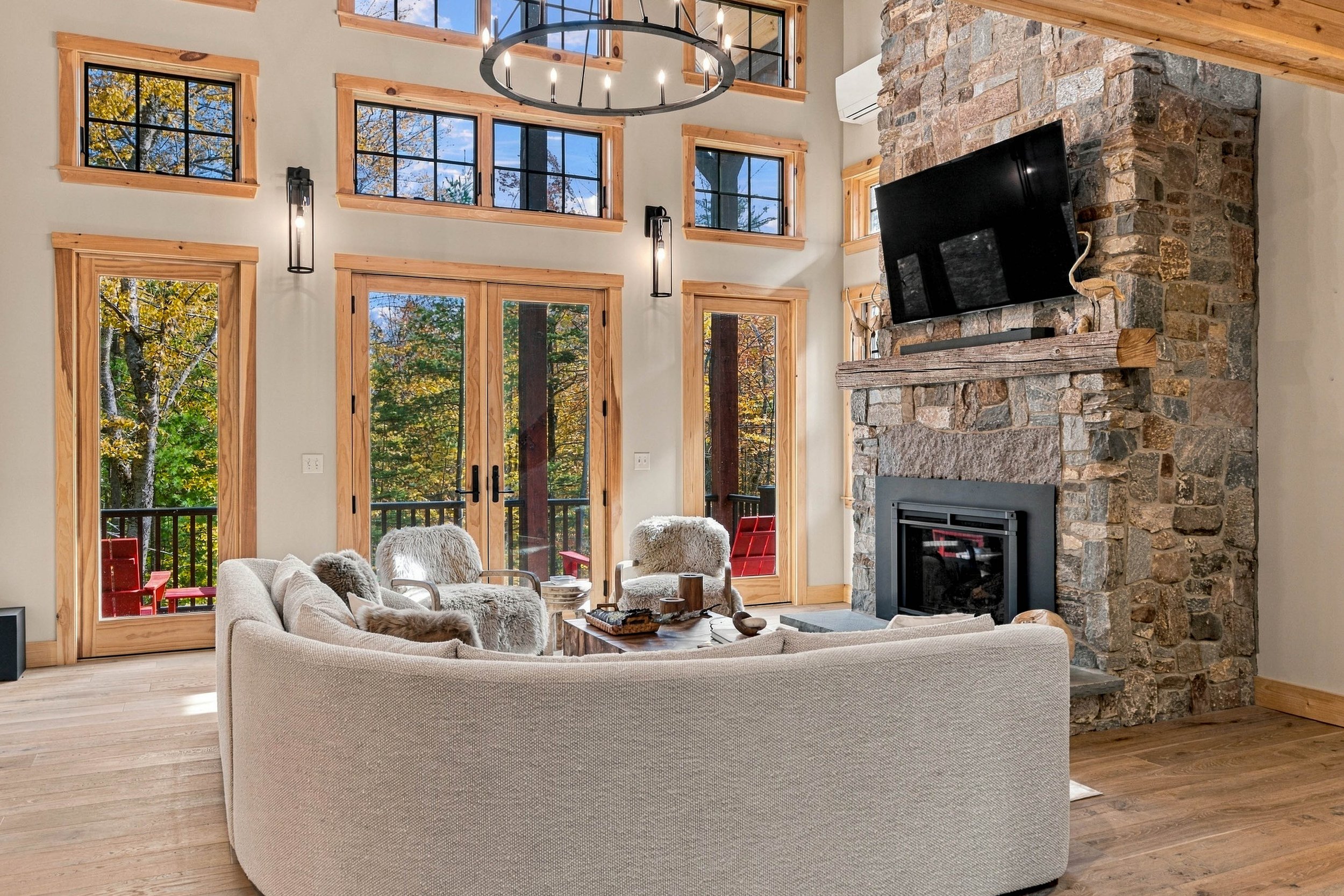Floor-to-ceiling windows, warm wood accents, and a dramatic stone fireplace create the ultimate mountain gathering space.