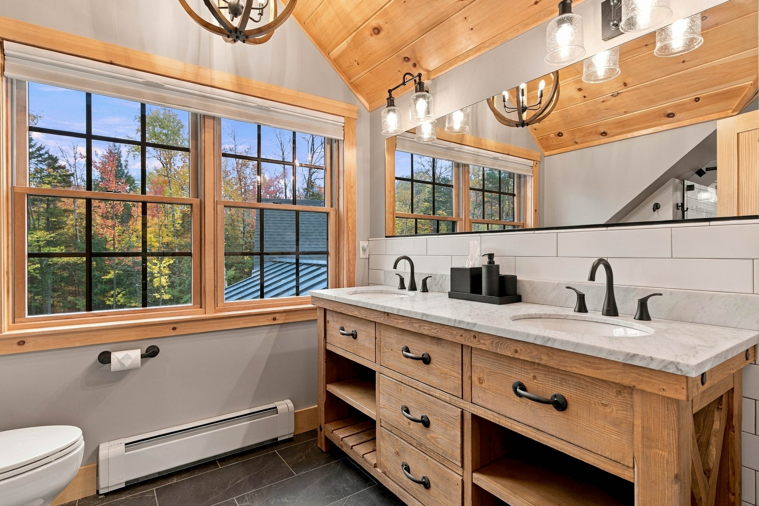 A beautifully appointed ensuite bathroom with double sinks, generous counter space, and lovely wooded views.
