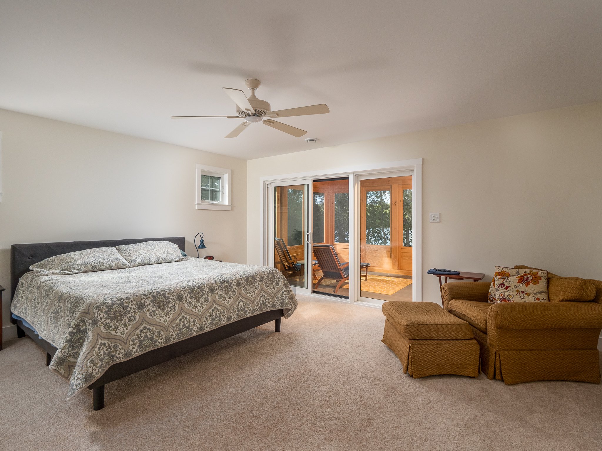 Spacious bedroom with bed, lounge chair, and sliding doors to outdoor area.