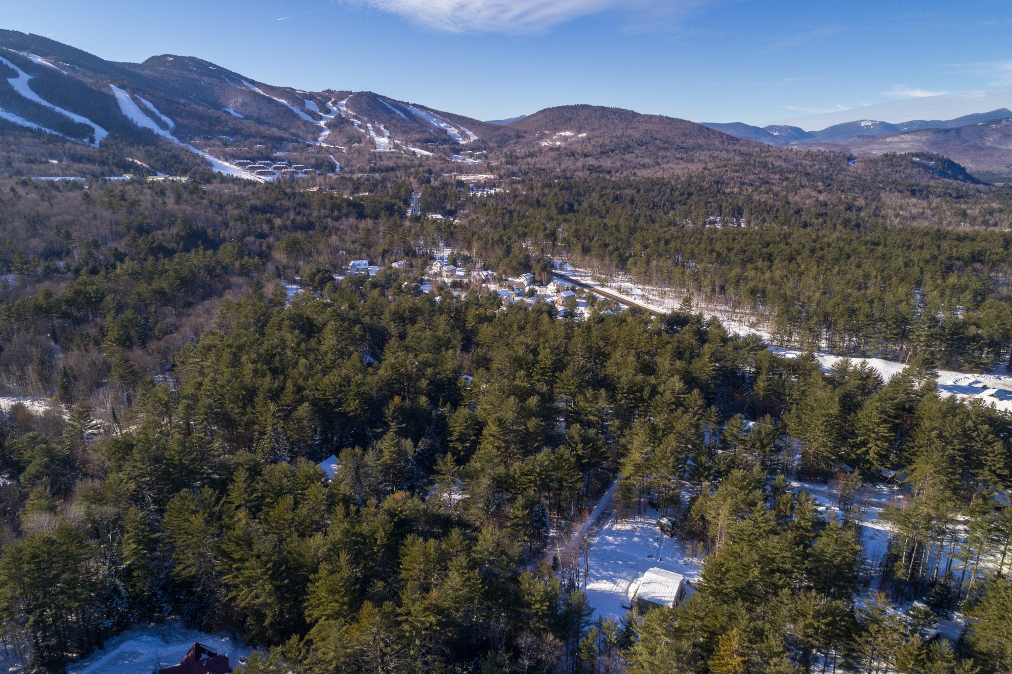 Aerial view of a snow-covered forest with mountain slopes, New Hampshire landscape.