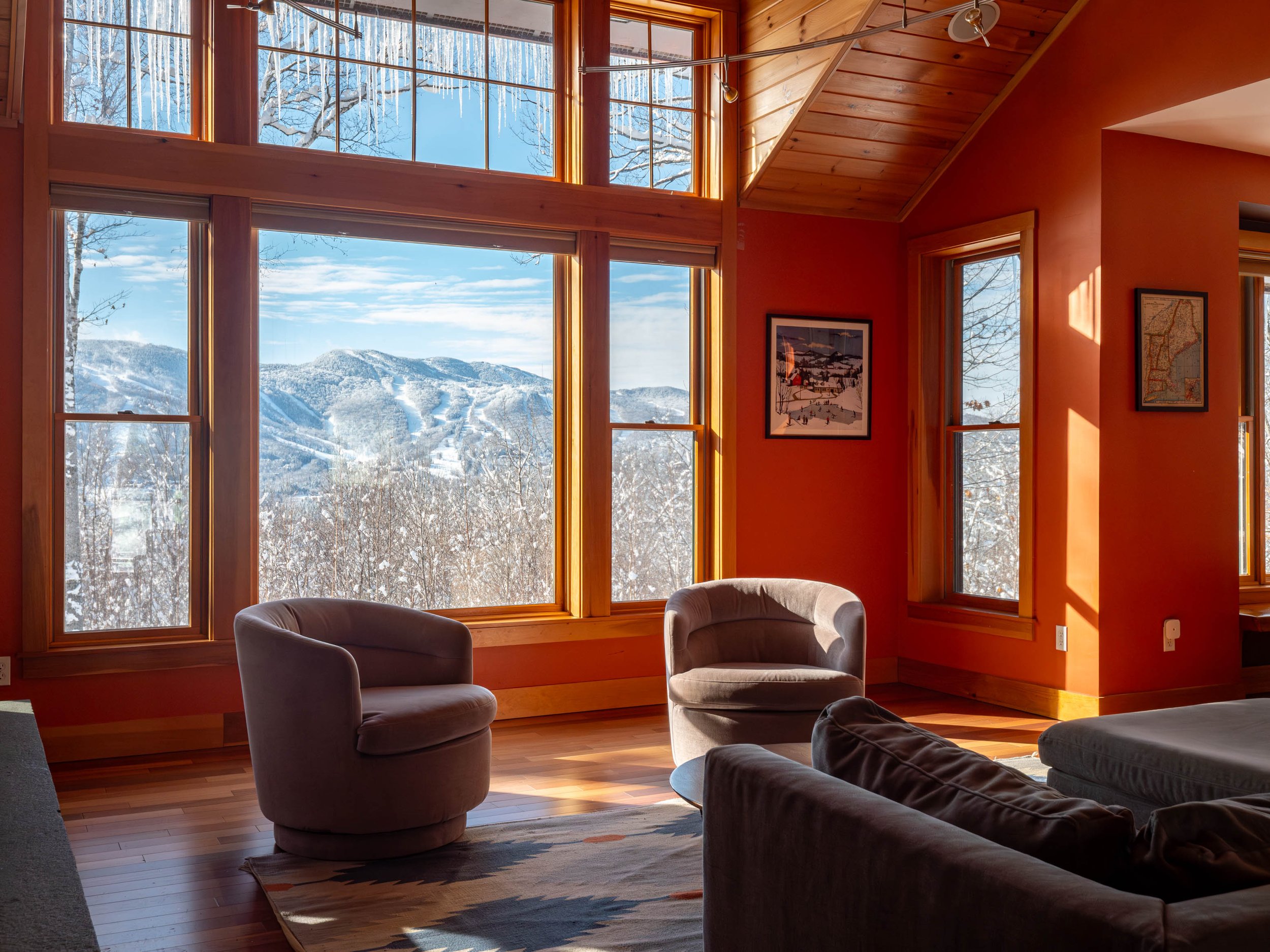 Living room with large windows, mountain view, and orange walls.