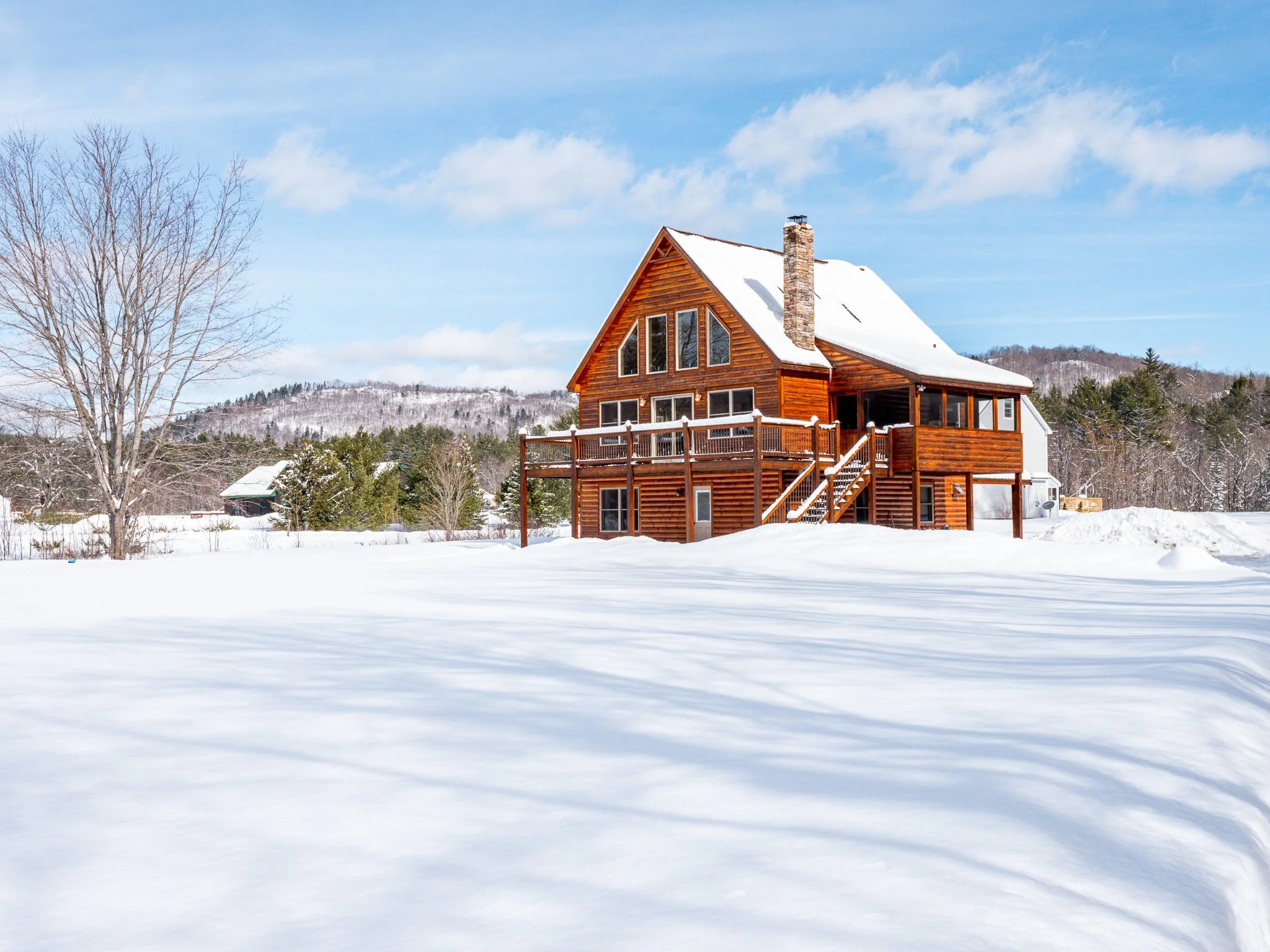 Wooden cabin in snowy landscape with blue sky and trees