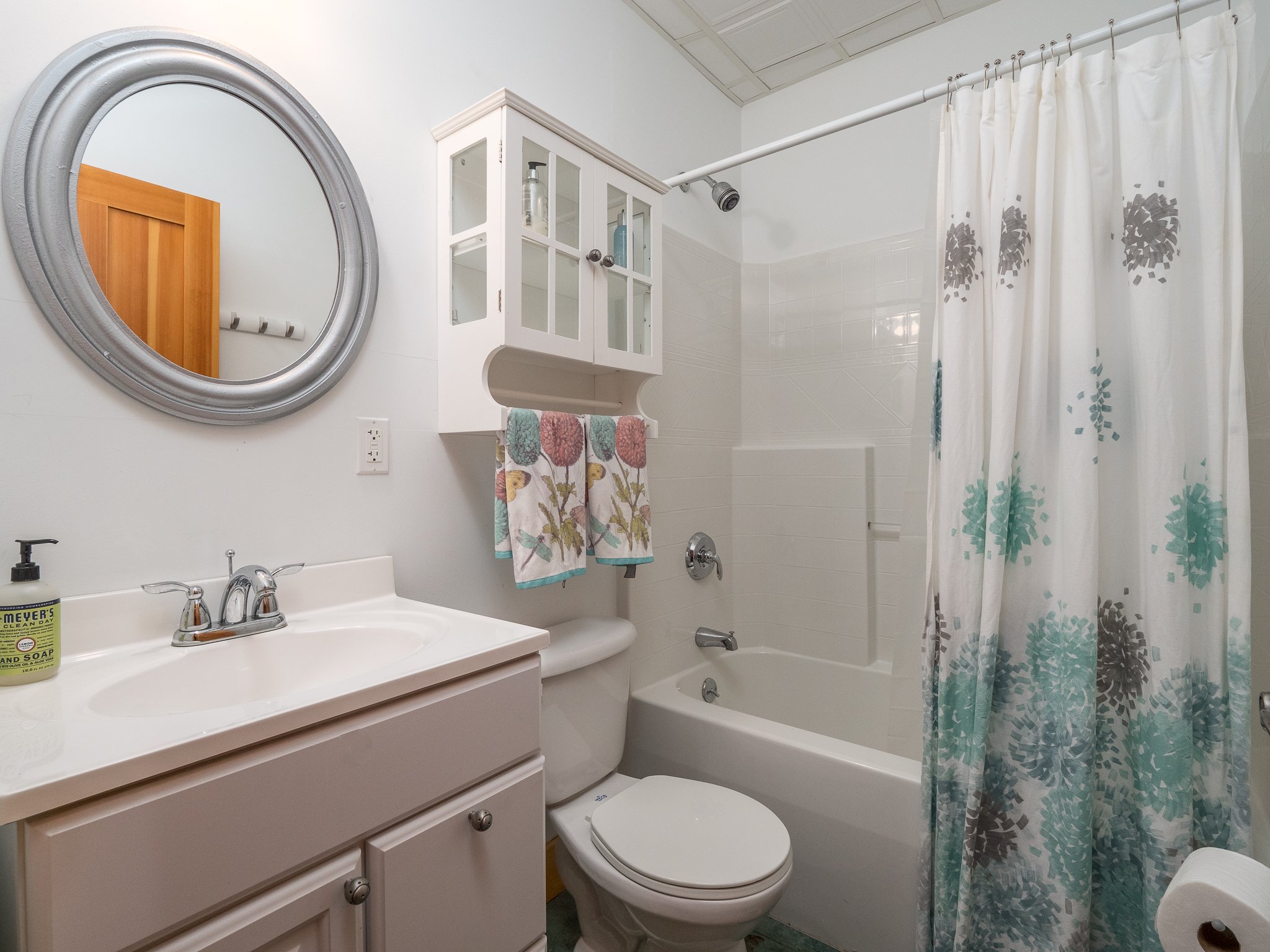 Bathroom with a sink, mirror, toilet, bathtub, and shower curtain.