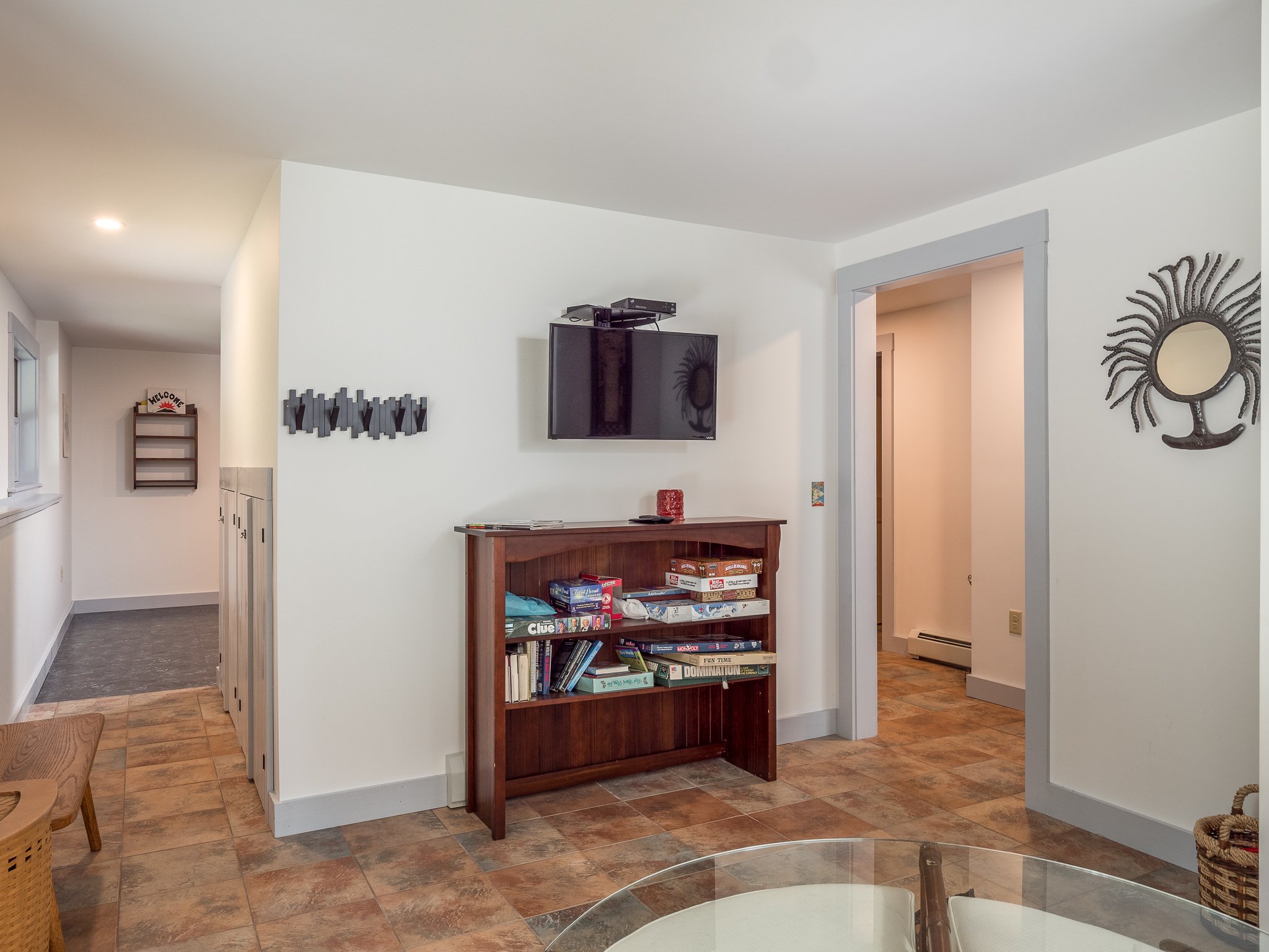 interior room with TV, bookshelf with board games, wall art, and tiled floor