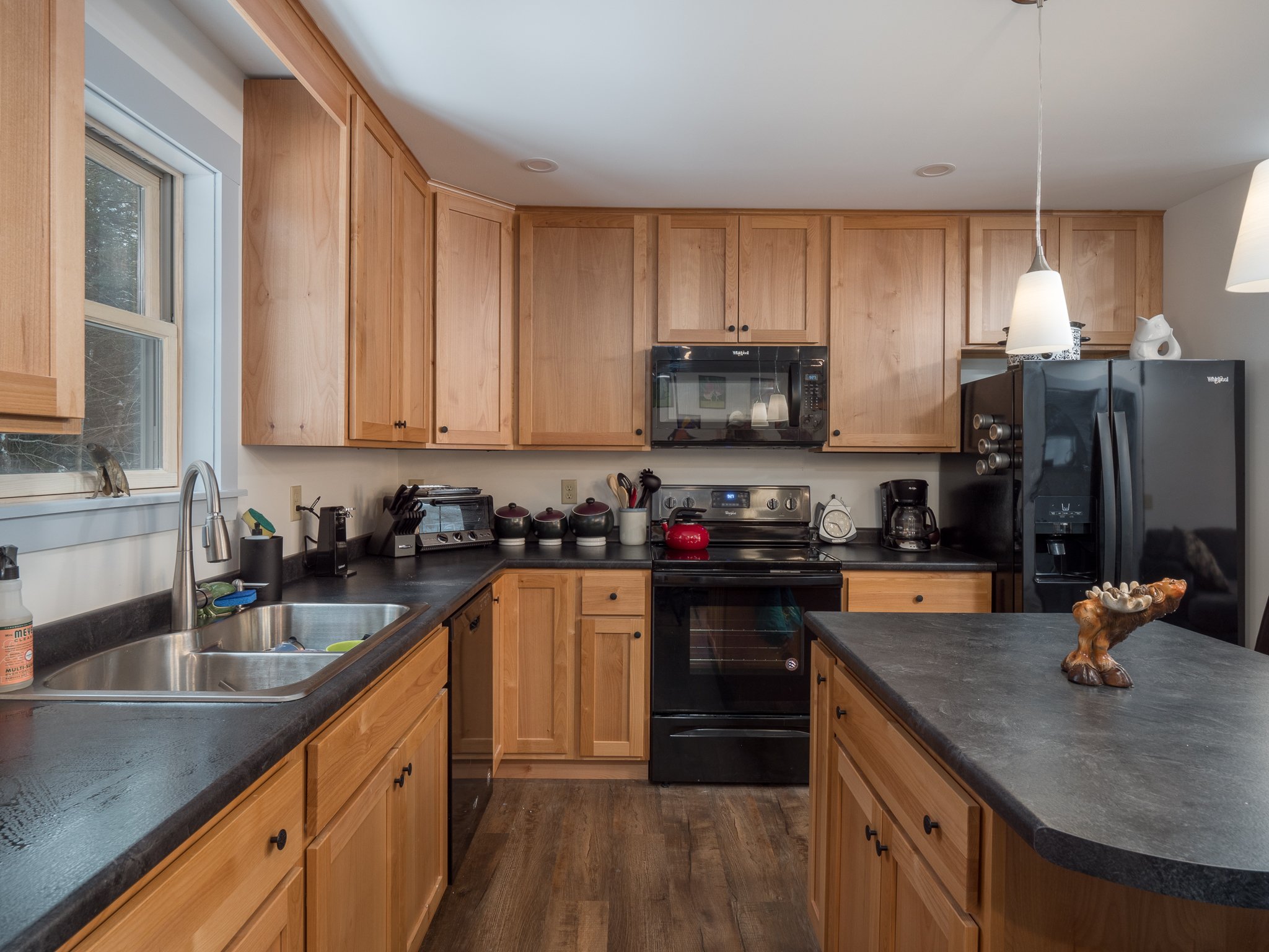 Modern kitchen with wooden cabinets, black appliances, and a central island.
