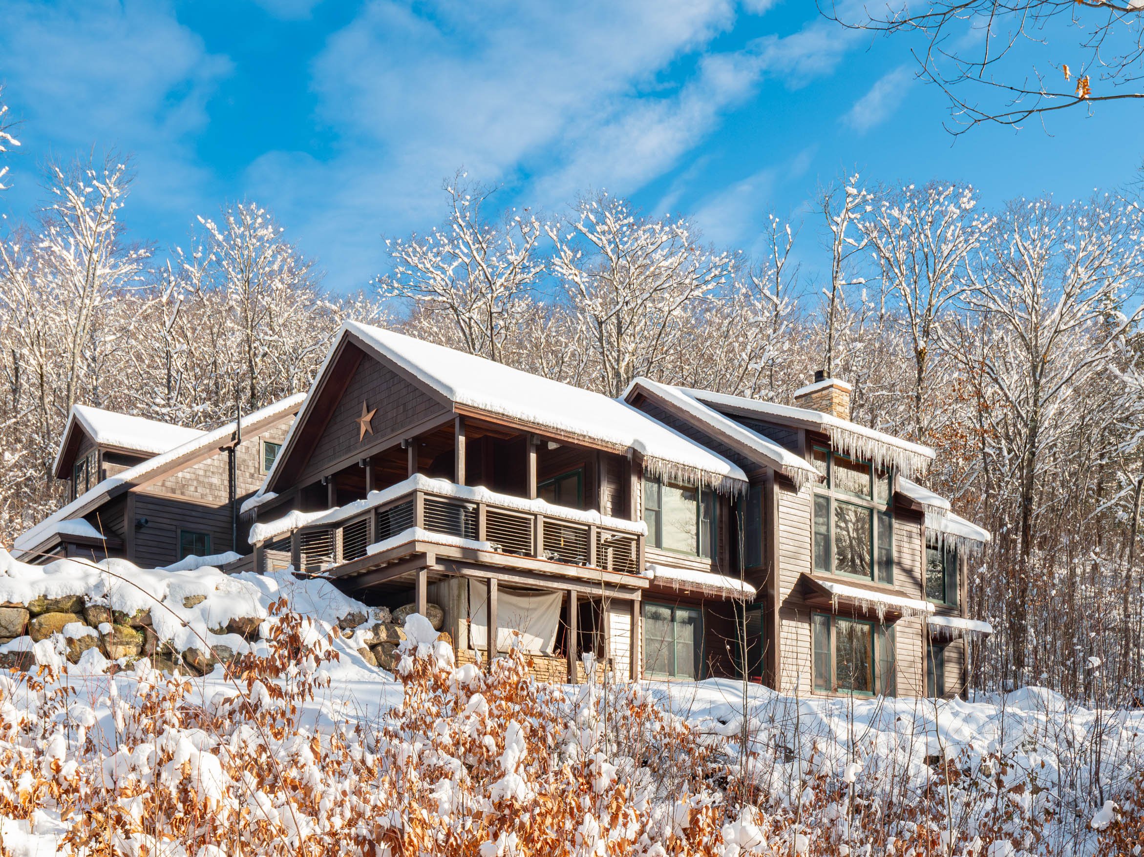 Wooden cabin in a snowy forest during winter, with icicles hanging from the roof.