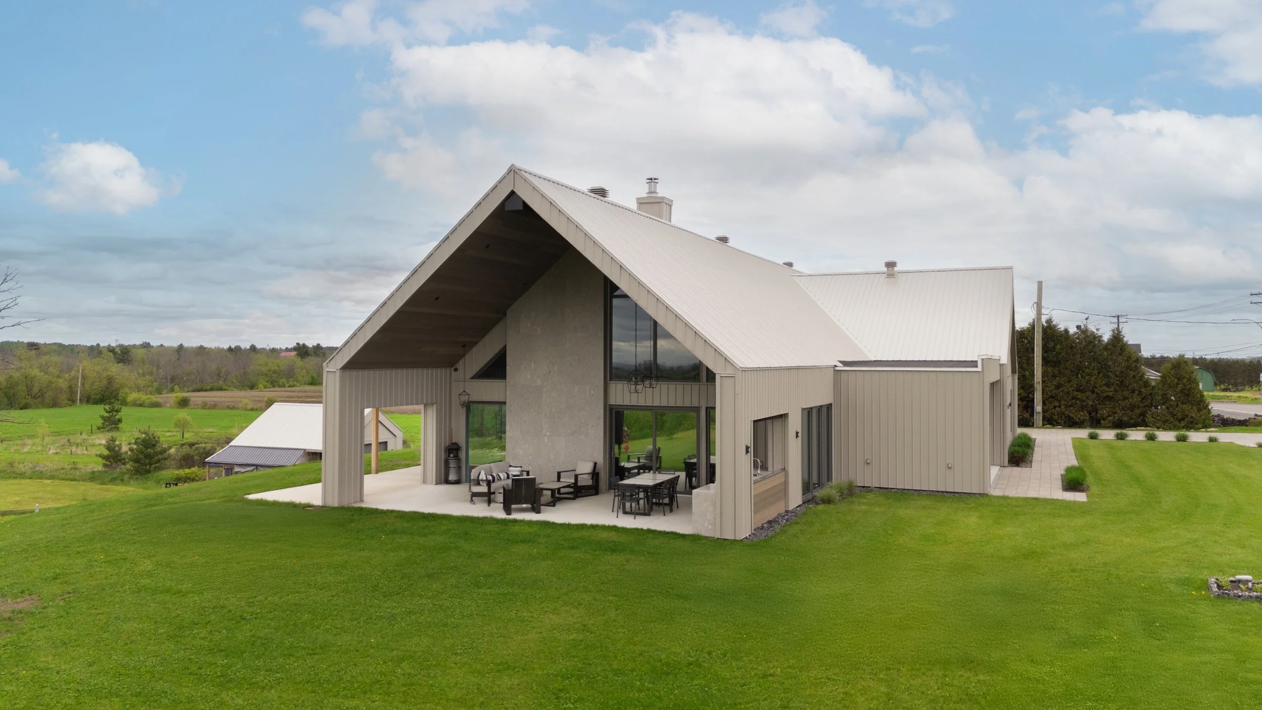 Photographie immobilière d’une maison contemporaine avec revêtement métallique et grandes fenêtres réalisée par Pixel Fabrique.