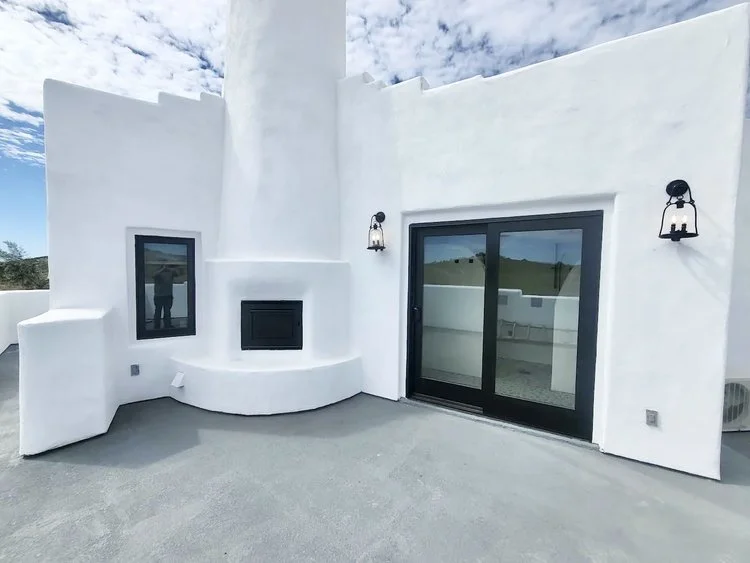 Minimalist white rooftop patio with fireplace and black-framed windows.