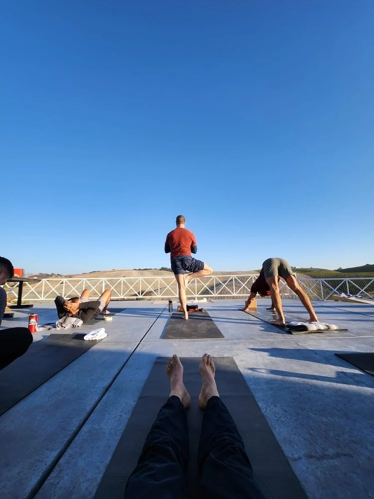 Group of people doing outdoor yoga on a rooftop with blue sky