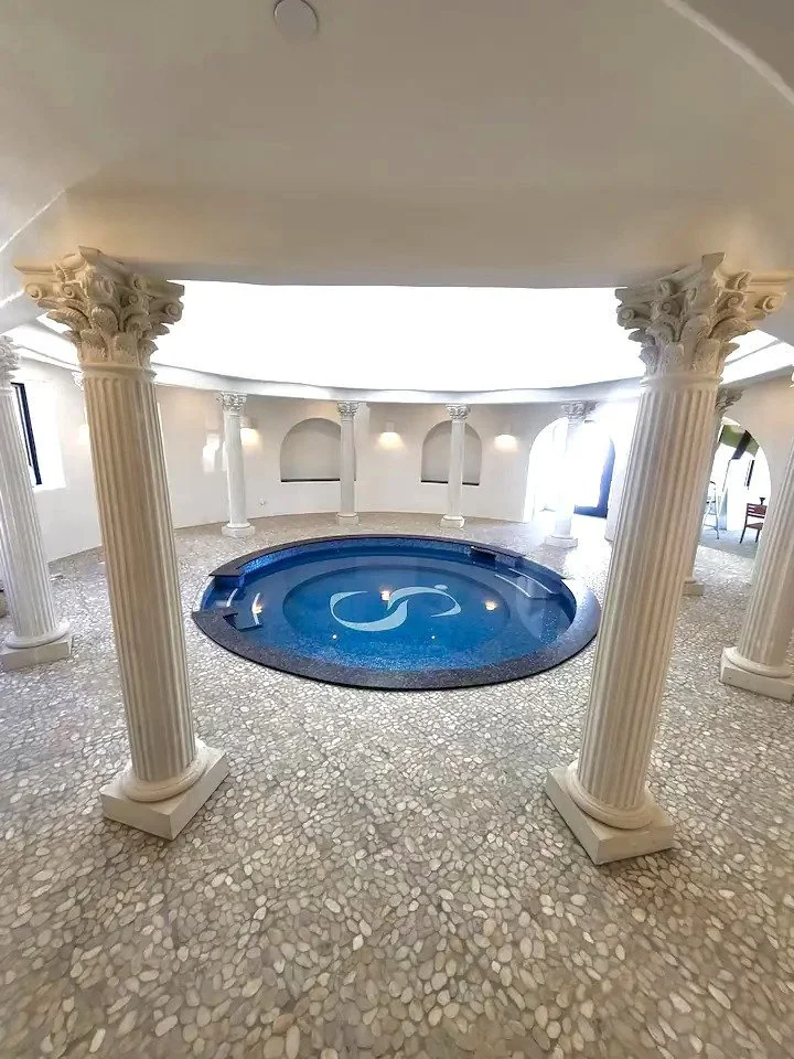 Indoor circular pool with ornate columns and tiled floor