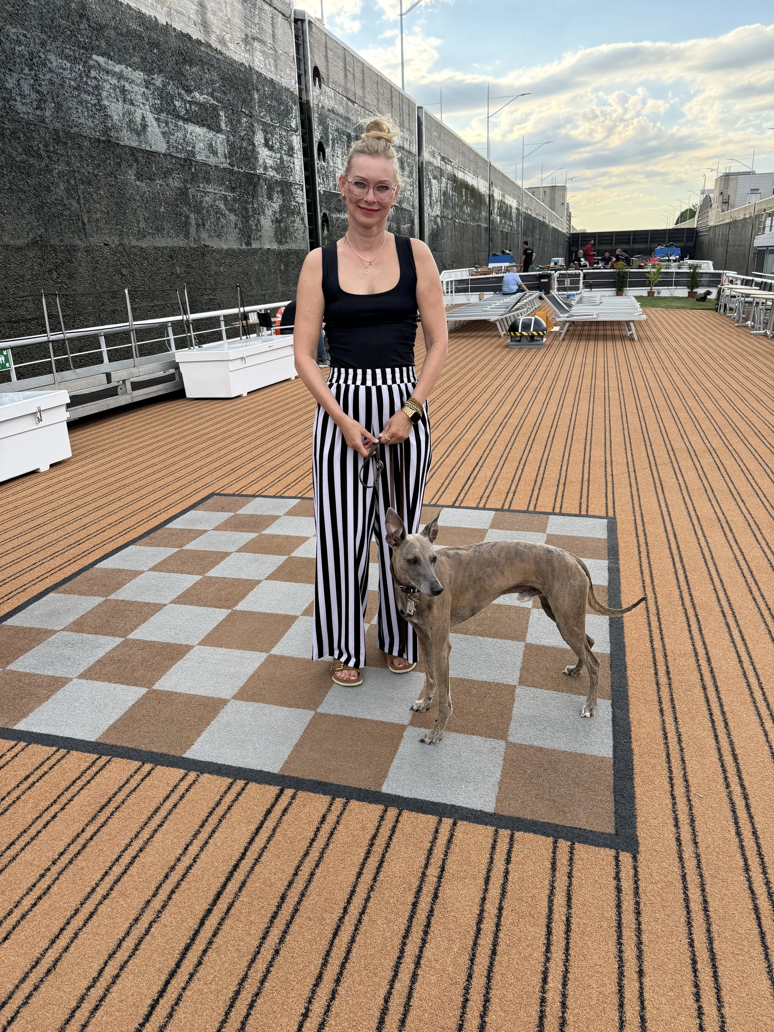 Frau mit Windhund steht auf einem Schiffsdeck