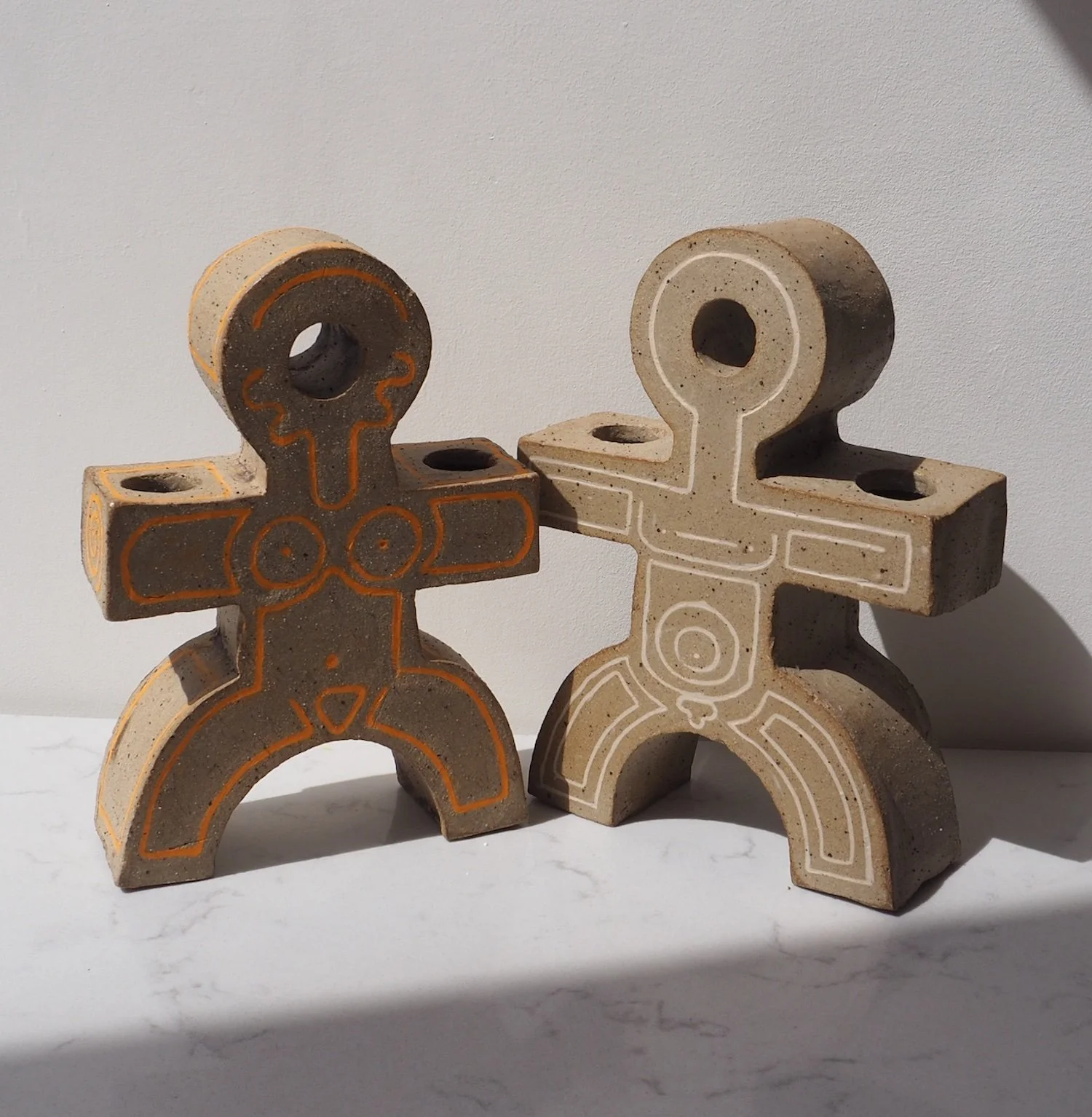 stoneware figrative made of concrete with slip inlay outlines, standing side by side against a white wall.