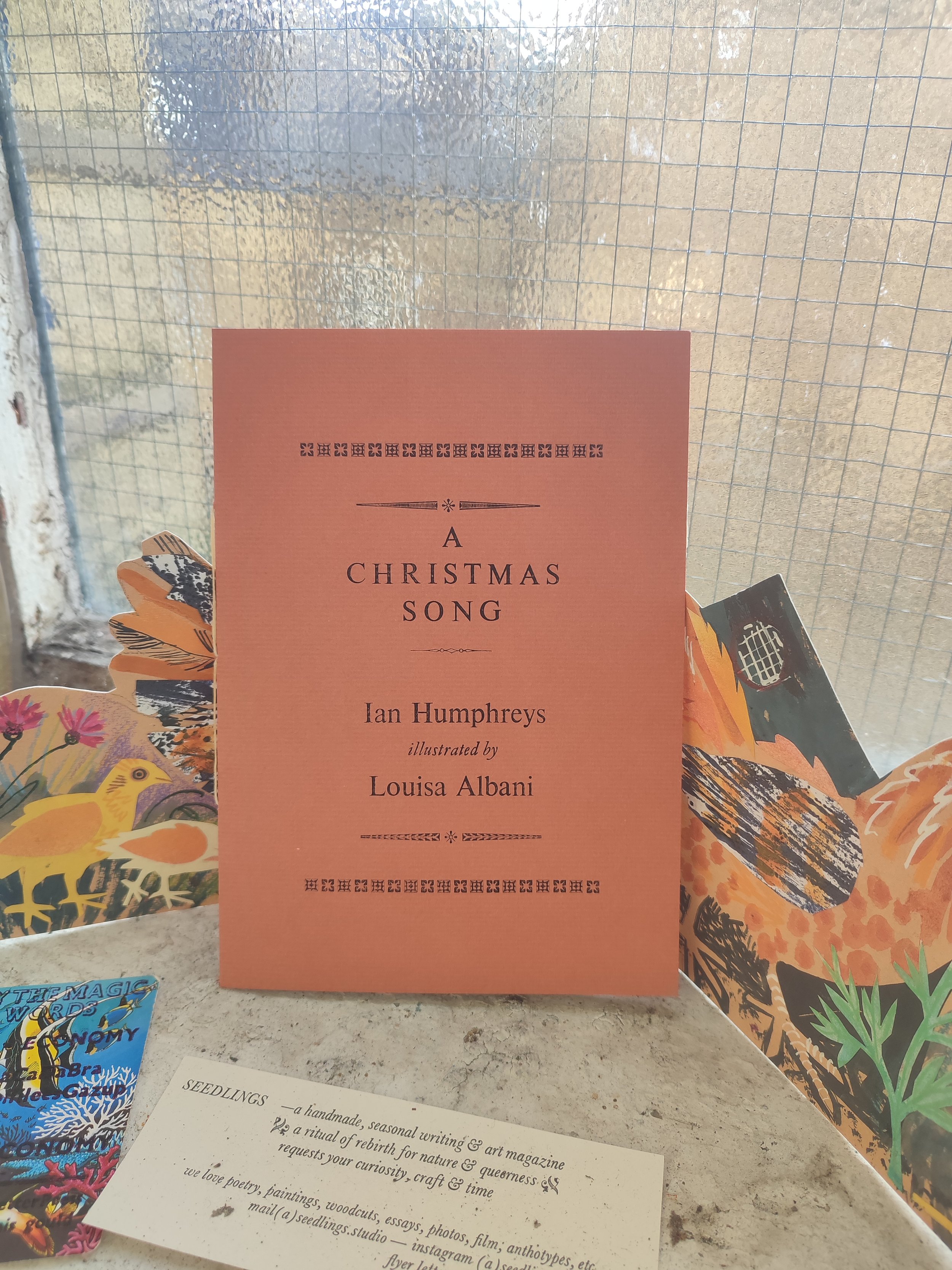 Cover page of Moresong Christmas pamphlet, 2025.  The cover is brick red, printed in black ink on textured paper. The type used is 24pt Times New Roman. Text reads: A Christmas Song. Ian Humphreys, illustrated by Louisa Albani.