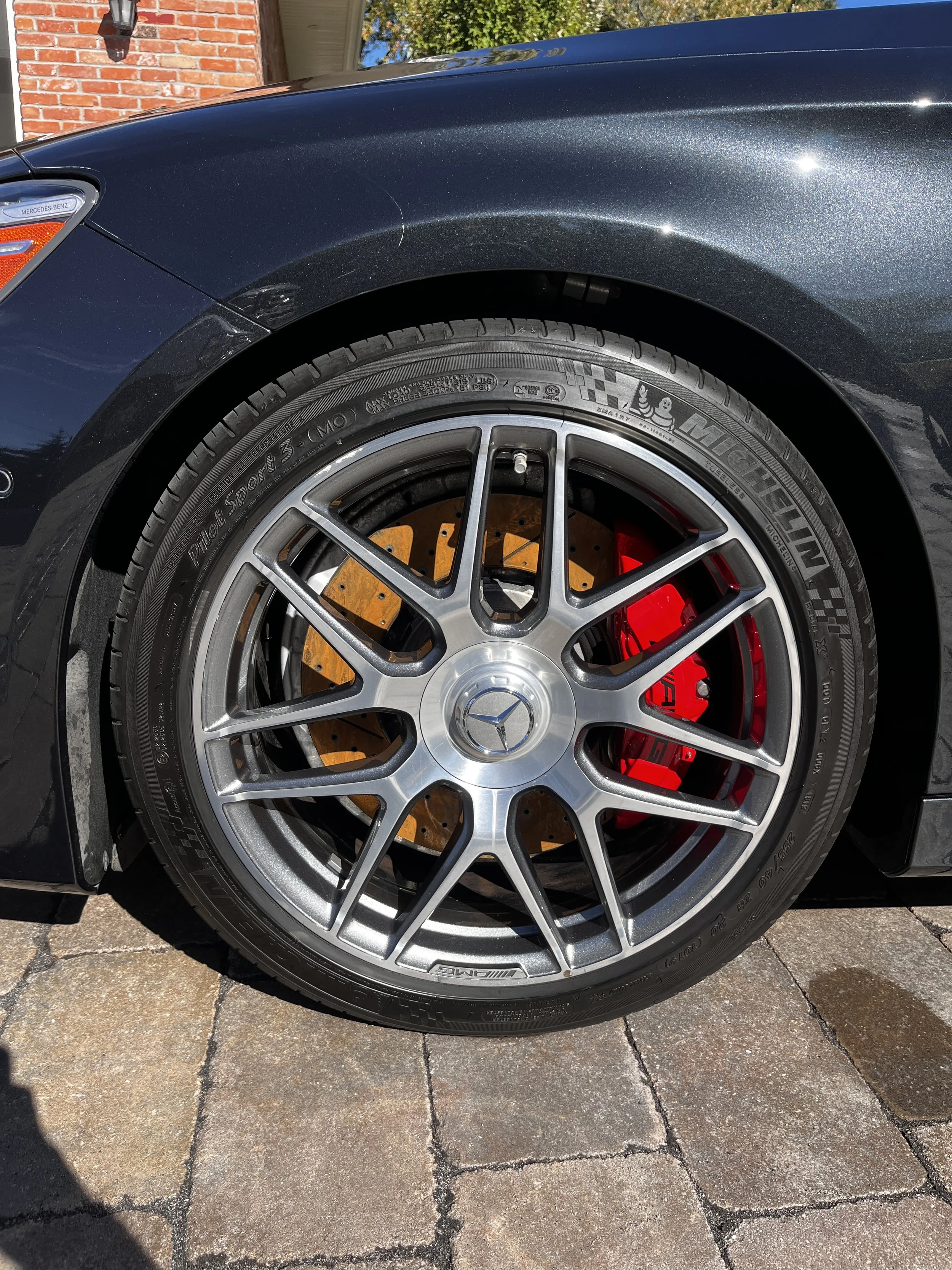 Close-up of a Mercedes-Benz car wheel with AMG branding, showing a silver alloy rim, Continental tire, and drilled brake disc.