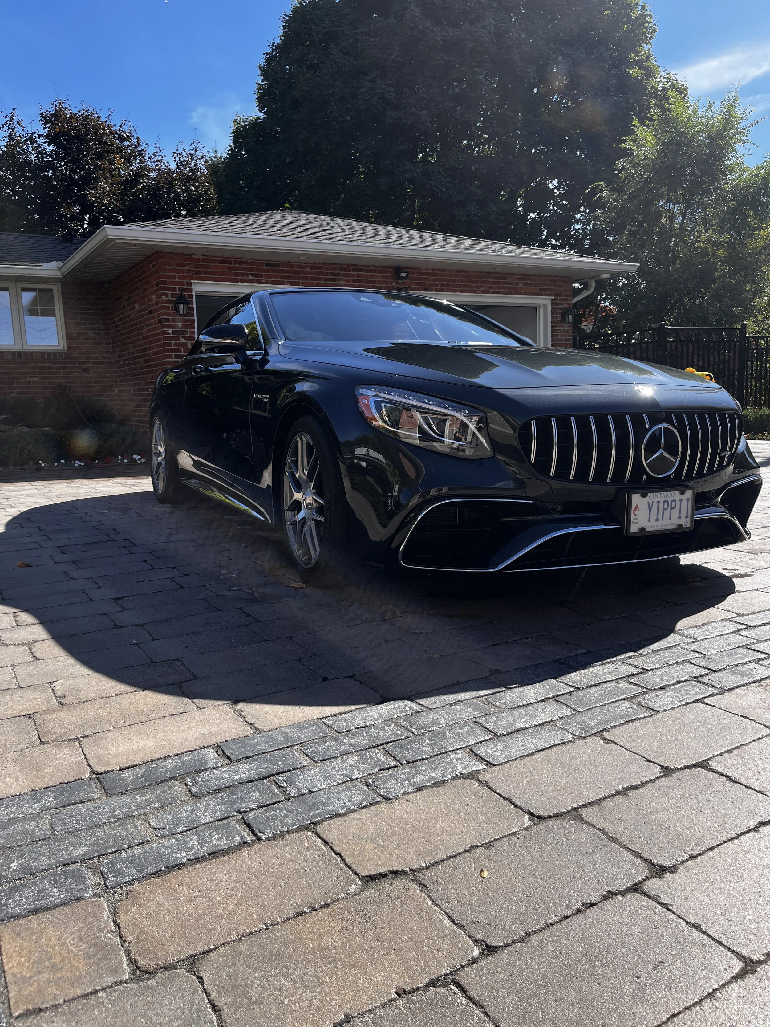 Close-up of the front of a black modern car parked outdoors on a sunny day.