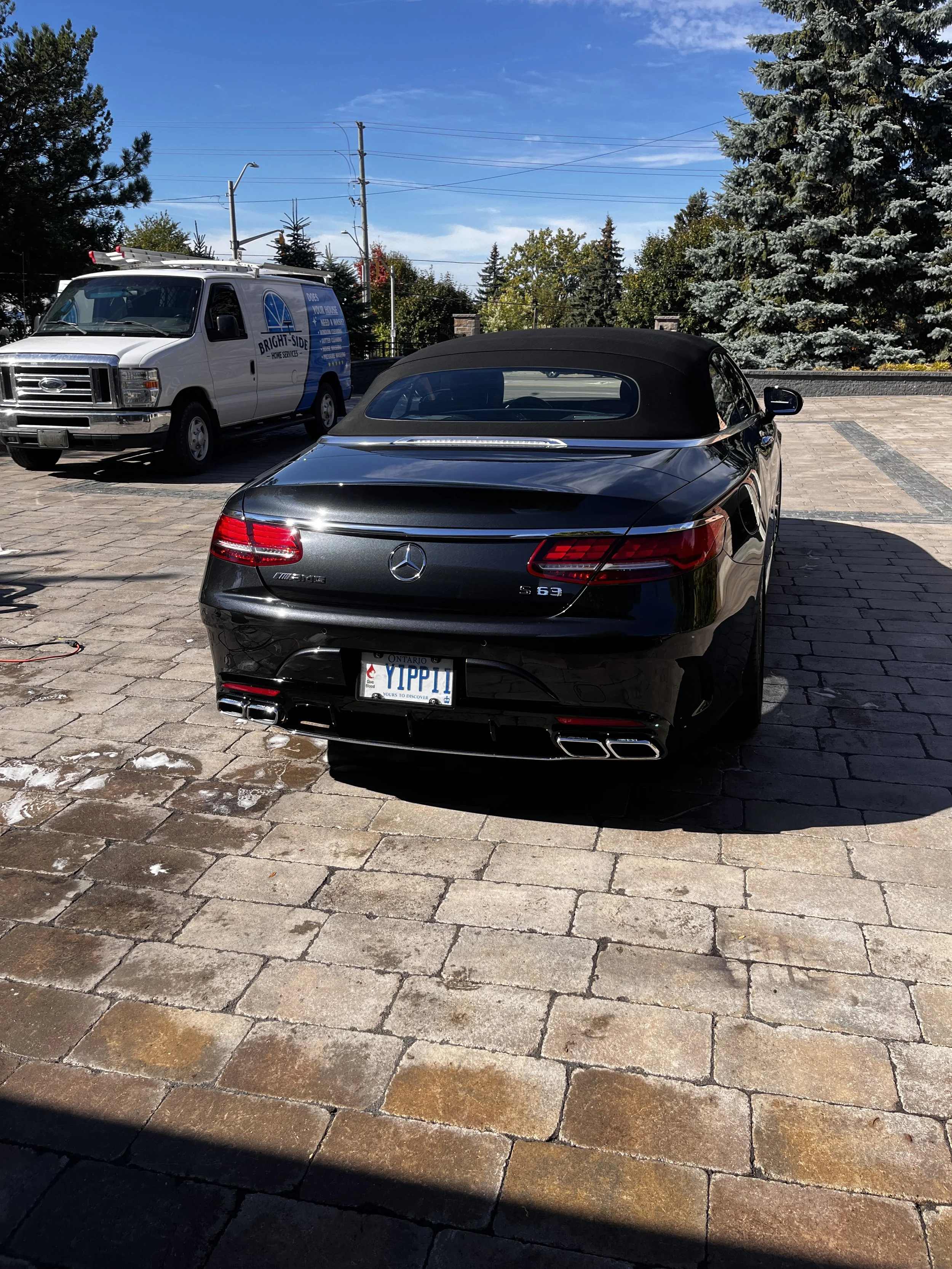 Interior view of a black Mercedes-Benz AMG sports car with leather seats, dashboard, and steering wheel, parked outdoors on a sunny day.