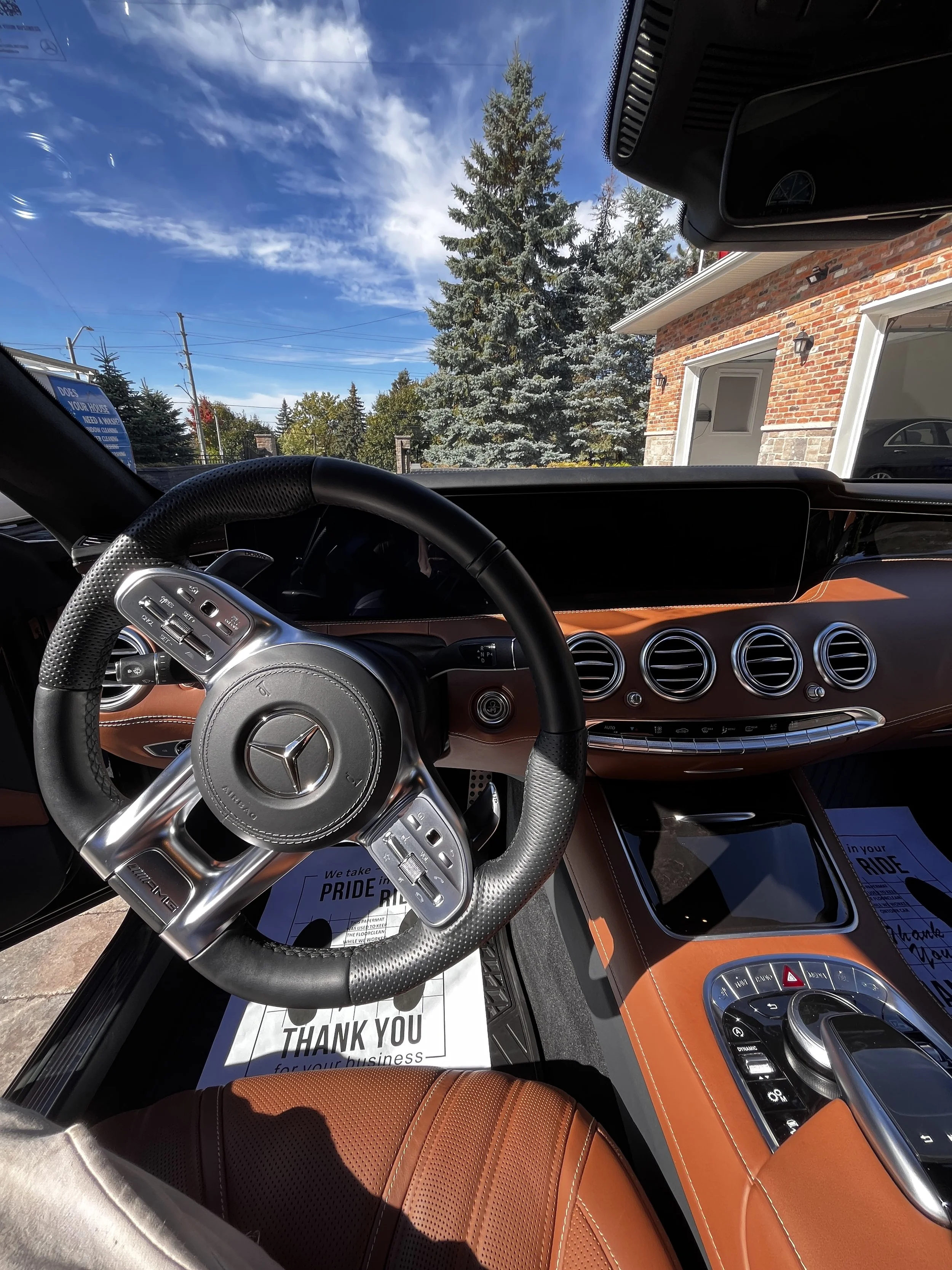 Interior of a luxury car showing black leather seats, steering wheel, dashboard with controls, and center console.