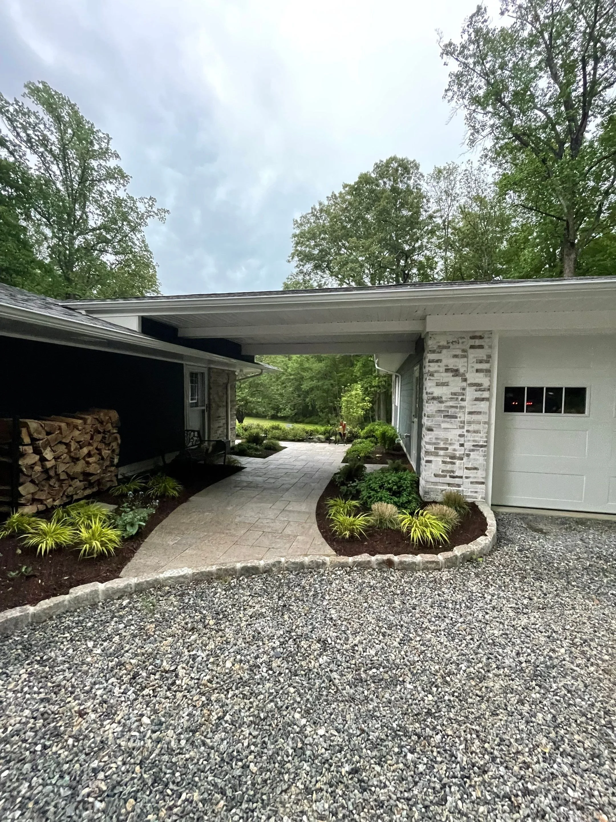 Garage entrance with stone walkway, foundation plantings, mulch beds, and decorative gravel driveway