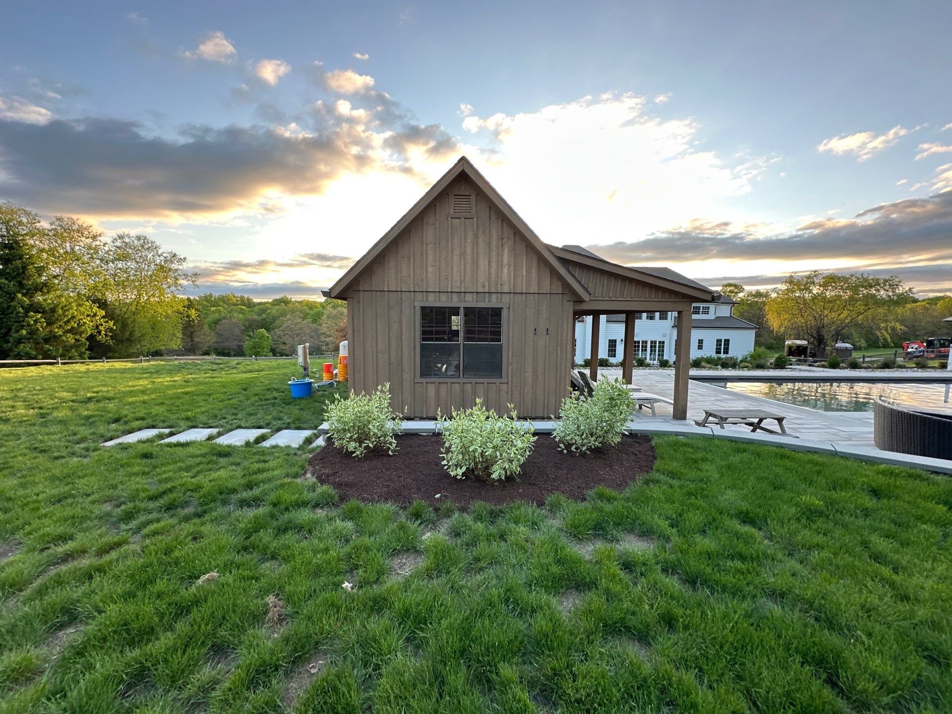 Paver patio, pool landscape and pool house with plantings