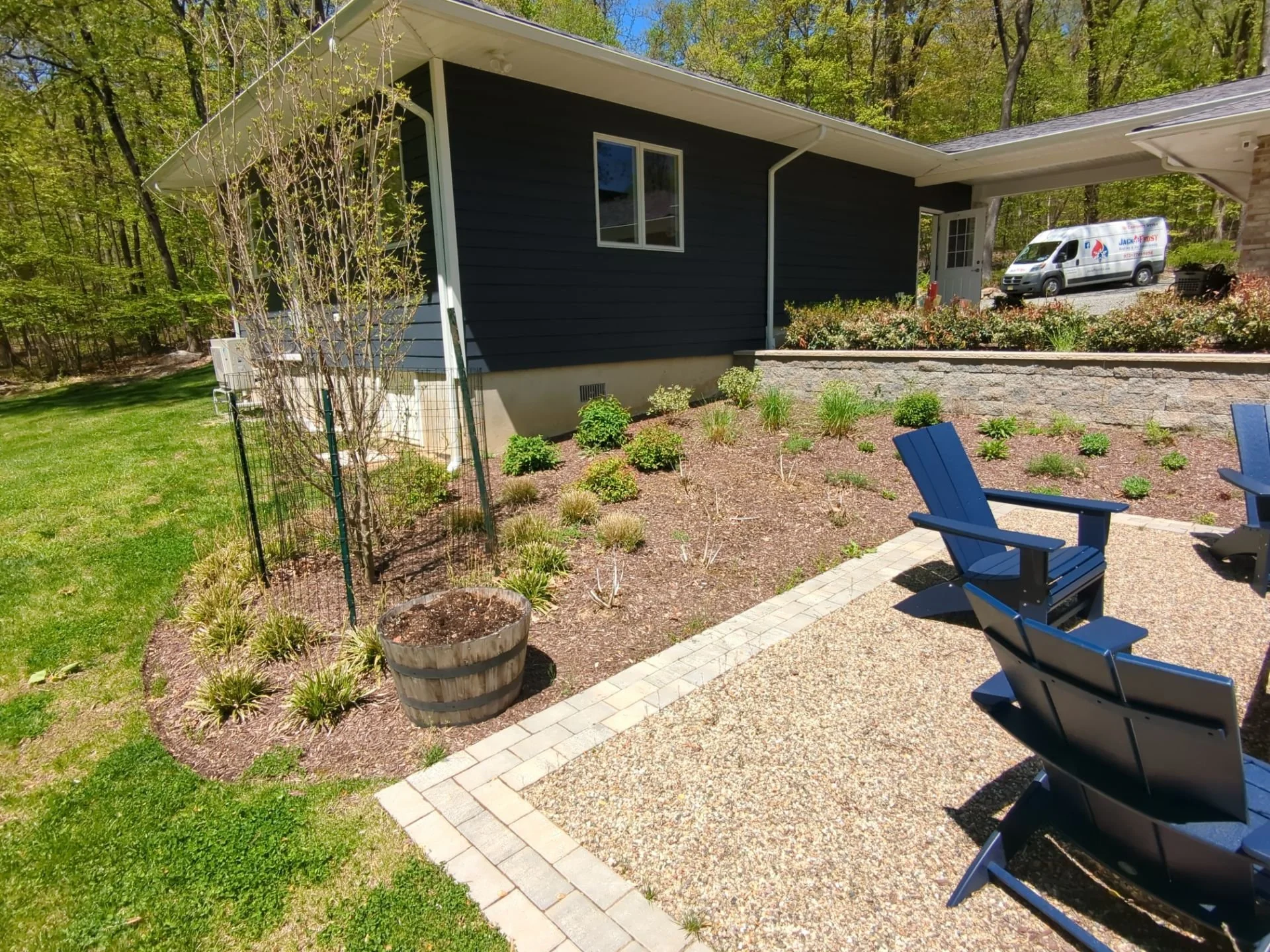 Backyard fire pit patio with Adirondack chairs, pea gravel, paver borders, and landscaped garden beds