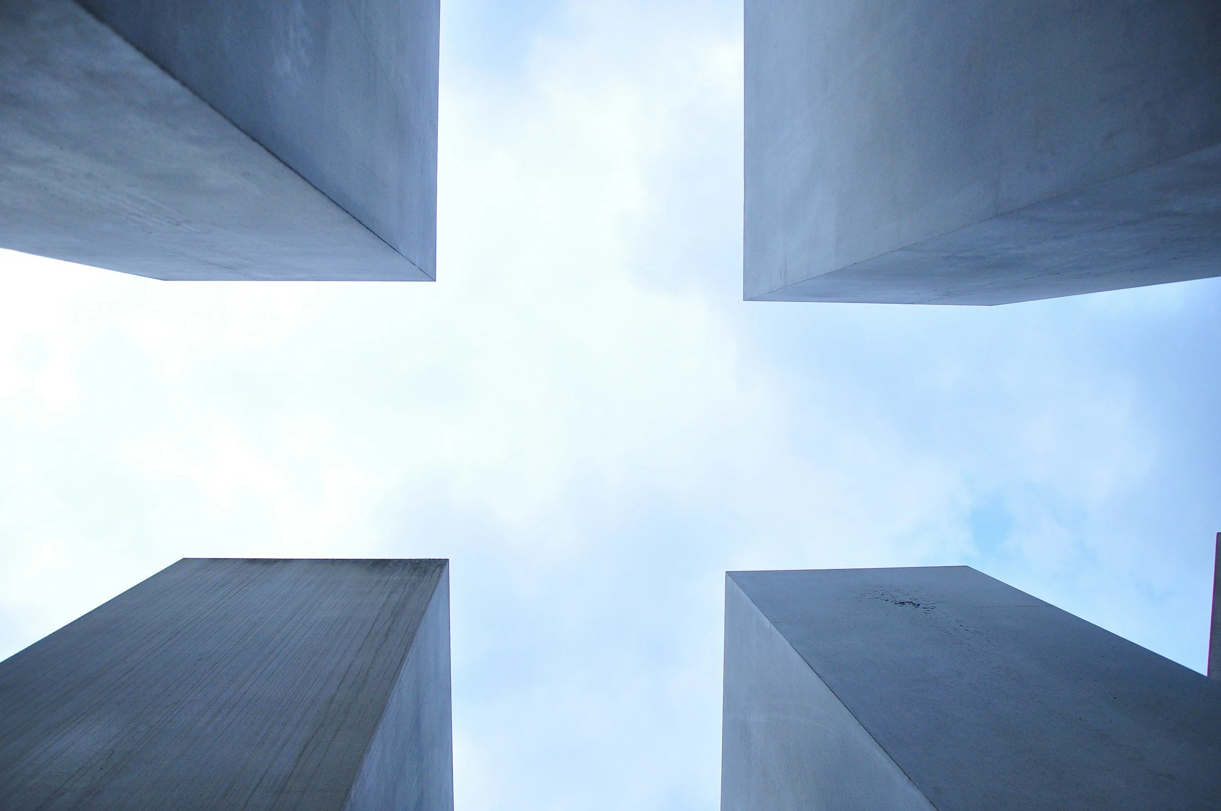Looking up at the sky between four tall concrete buildings.