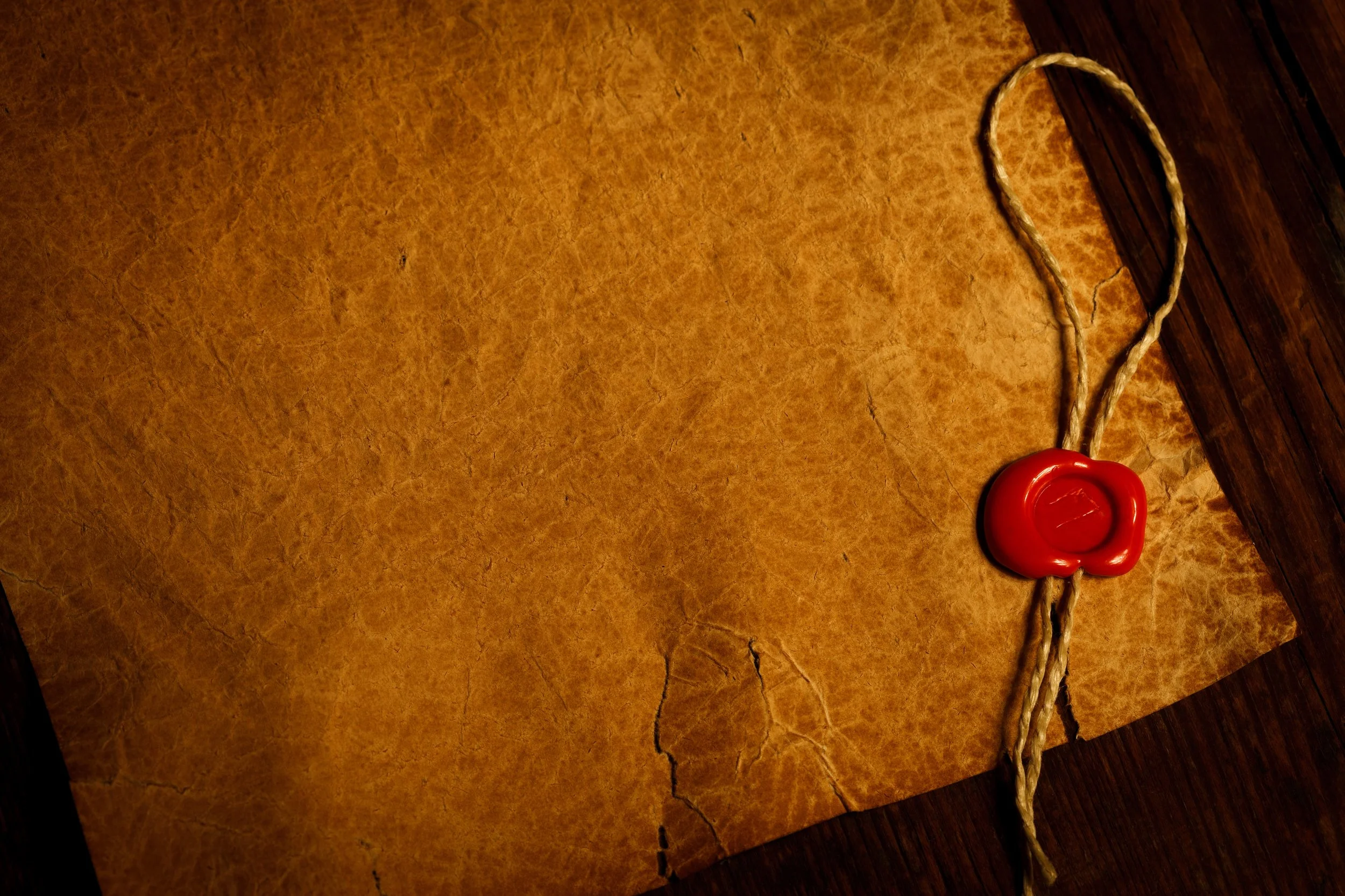 A red wax seal and a twisted rope on a wooden table.