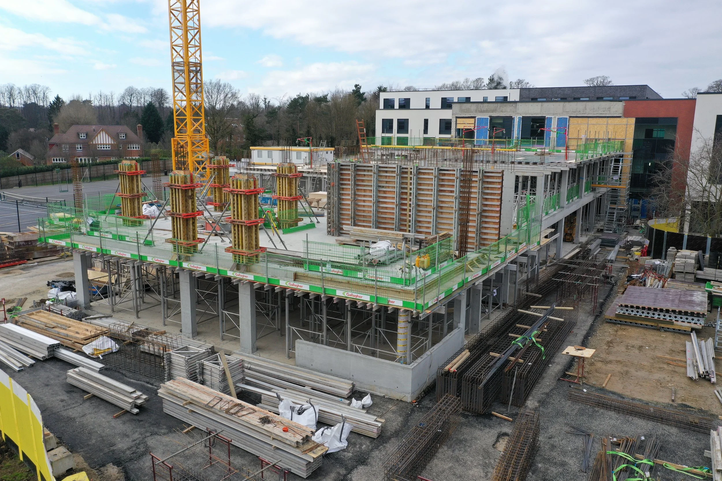 Construction site with a multi-story building under construction, surrounded by construction materials, scaffolding, and equipment.