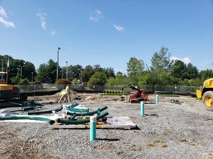A playground installation is in progress with pipes for drainage ready to be installed.