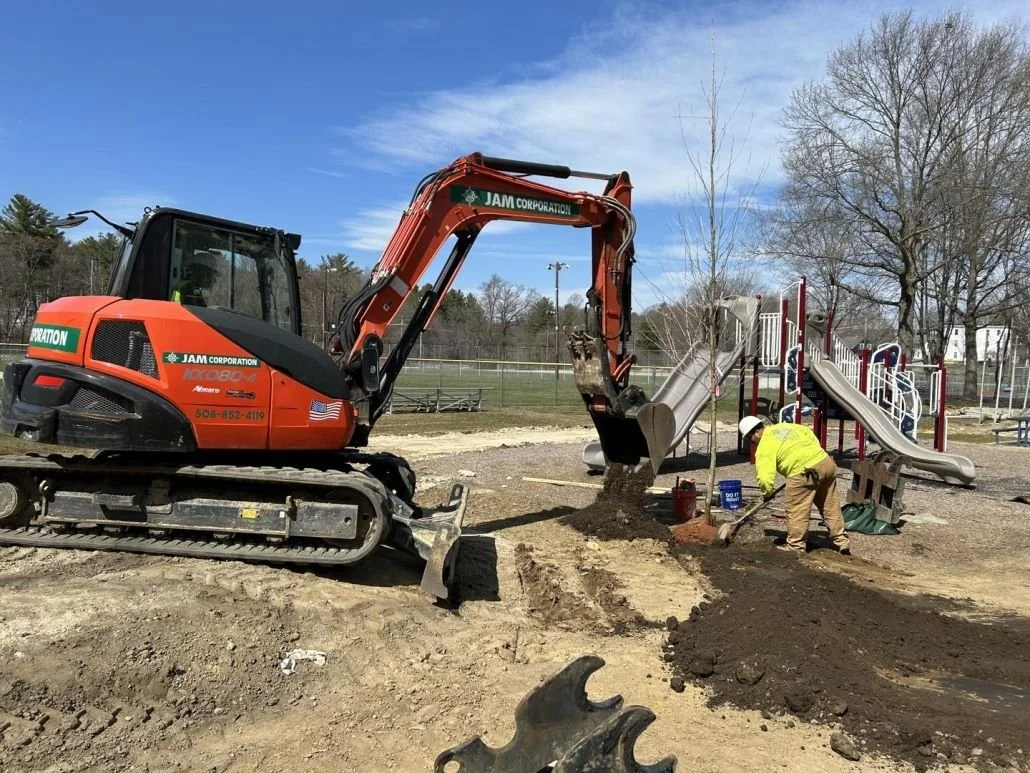 An excavator is filling in new dirt around a tree in the new playground  at Southbridge's McCann Field and Playground.
