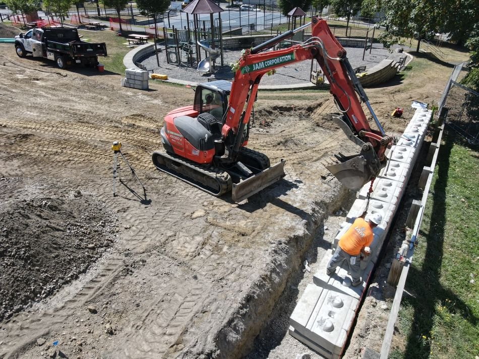 An excavator builds a stone wall for the new Grant Square Community Gardens municipal project.