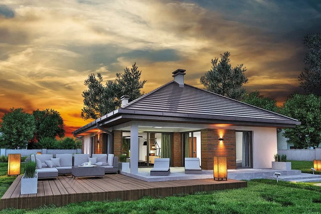 Modern house with a wooden deck and outdoor seating area, trees, and a colorful sunset sky in the background.