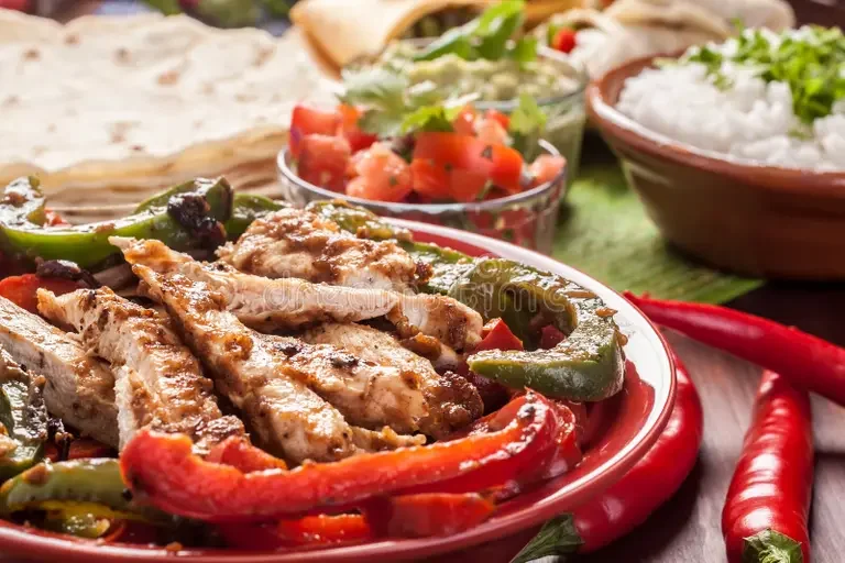 traditional-mexican-food-ingredients-chicken-fajitas-fajita-peppers-cilantro-lime-rice-tortillas-guacamole-salsa-43039296.webp